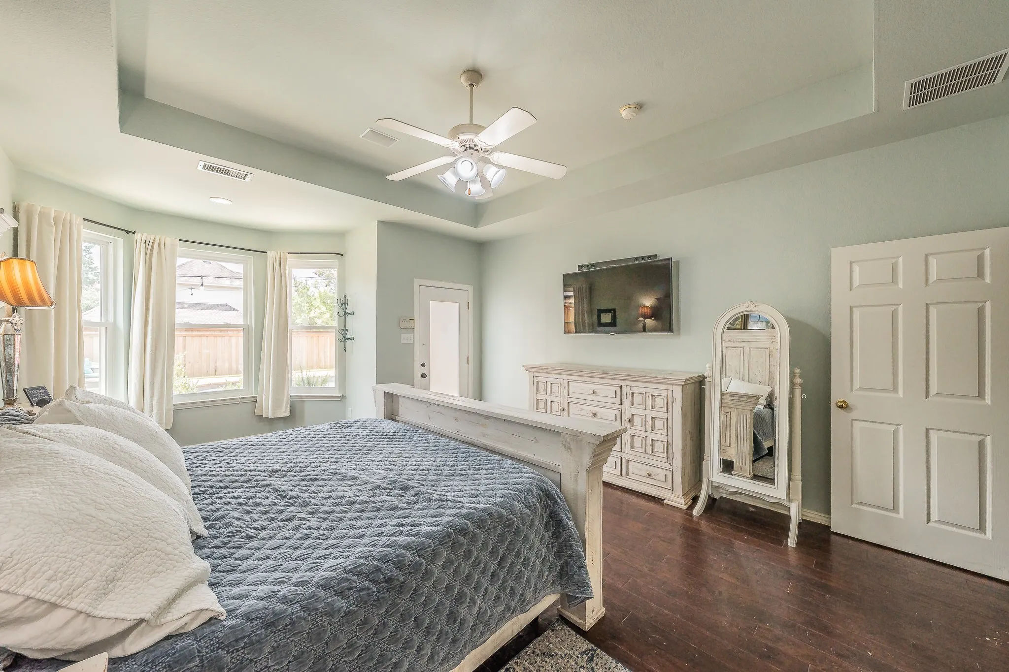 Room featuring a tray ceiling, ceiling fan, and dark wood-finish flooring