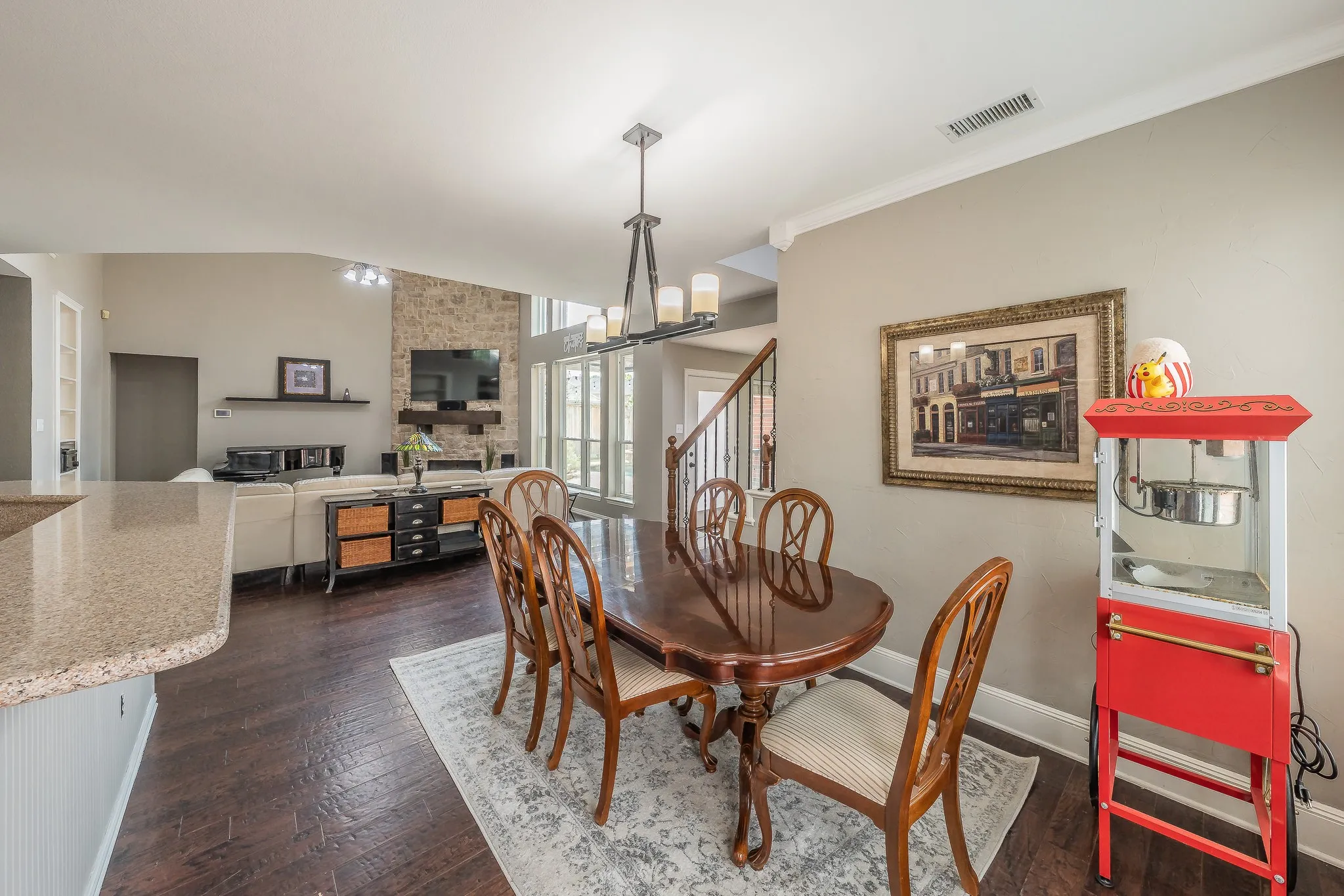 Open-concept living space featuring wood-finish flooring, a stone fireplace, and high vaulted ceilings