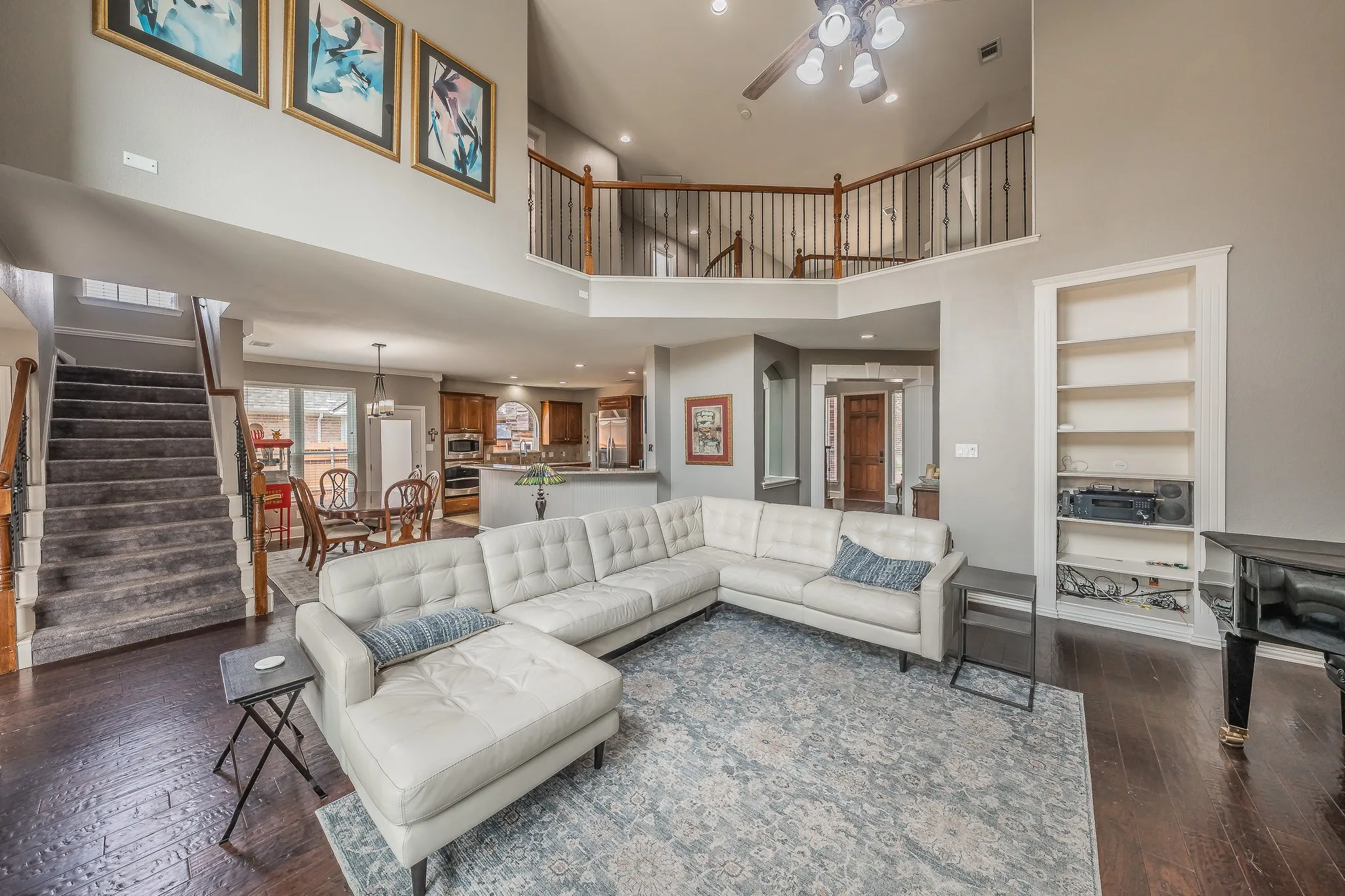 Expansive main living area featuring high ceilings, dark wood-finish flooring, and a large built-in shelving unit