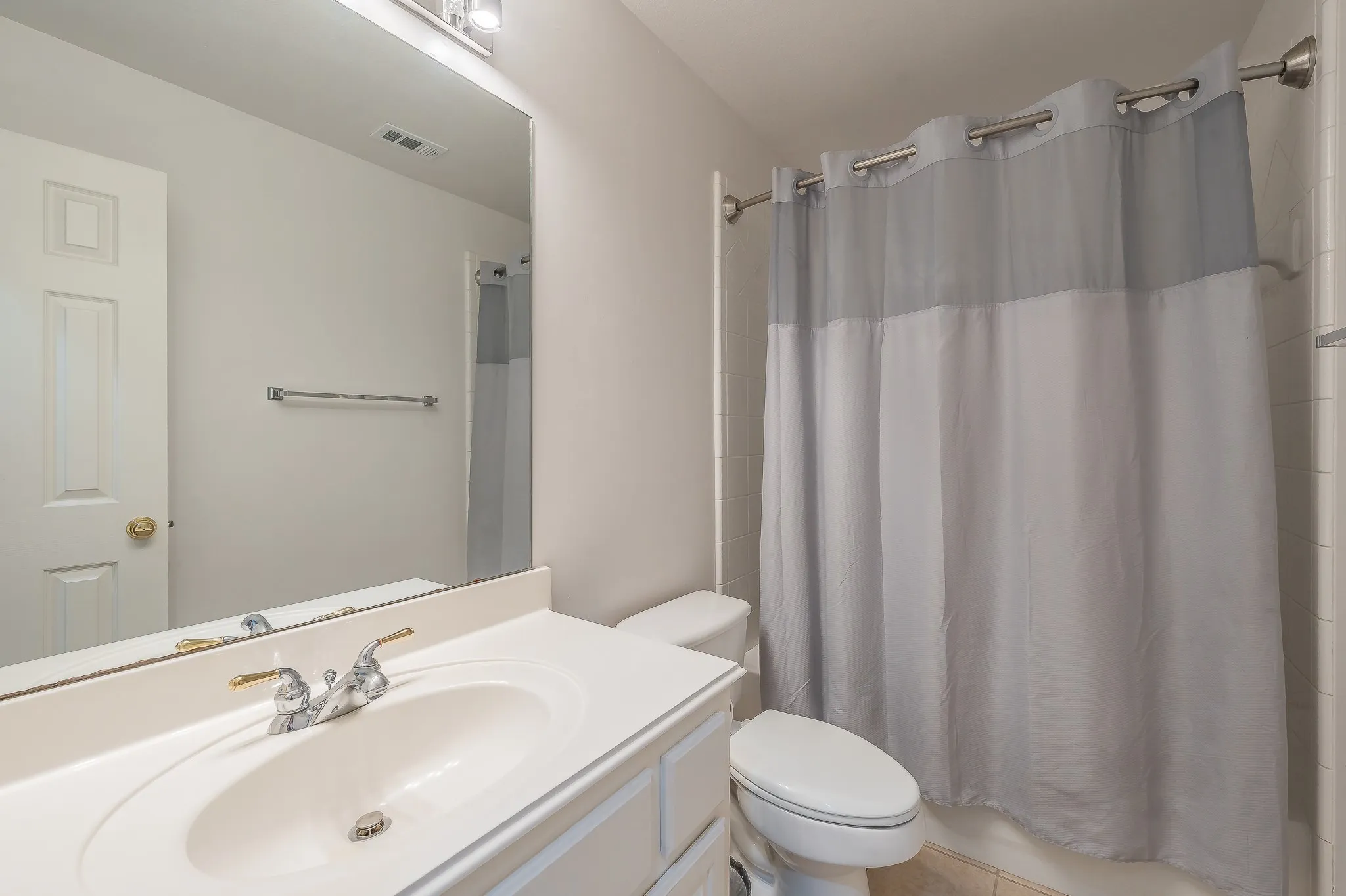 Bathroom vanity featuring an integrated sink, dual-handle faucet, and an expansive wall-mounted mirror