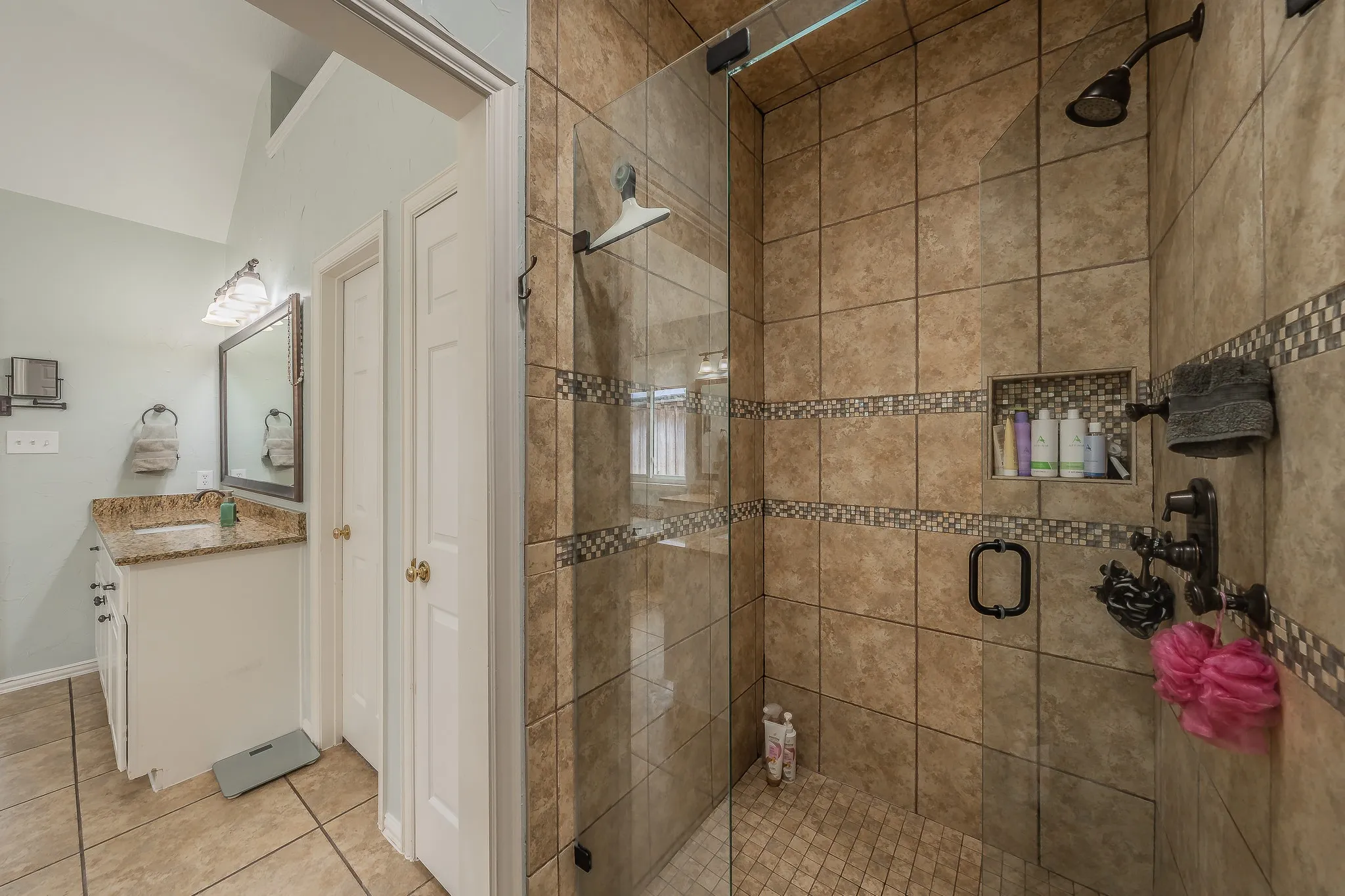 Tiled shower enclosure with a glass panel door and a built-in shower niche