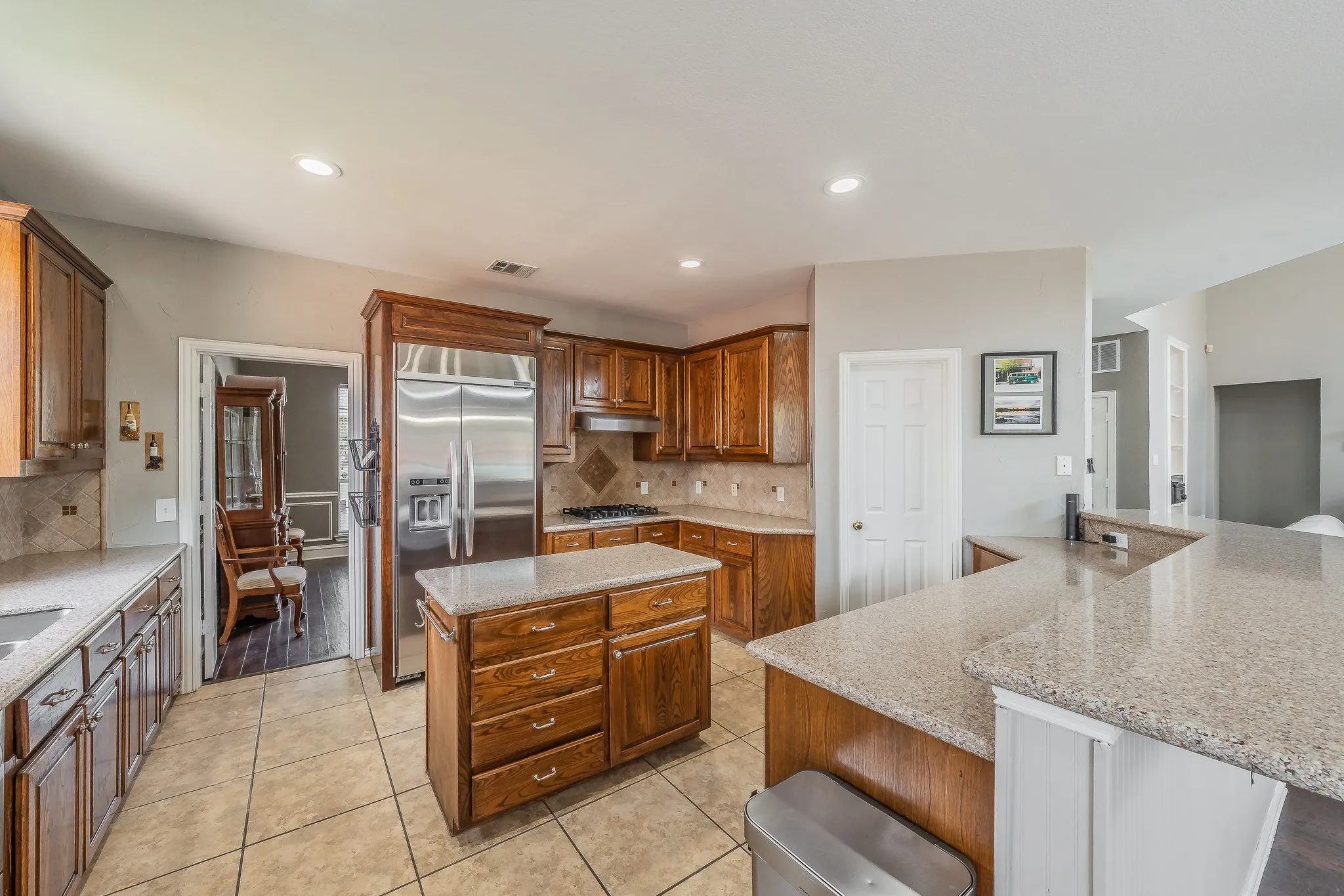 Kitchen featuring wood cabinetry, stainless steel appliances, a center island with storage, and a breakfast bar with stone-finish countertops