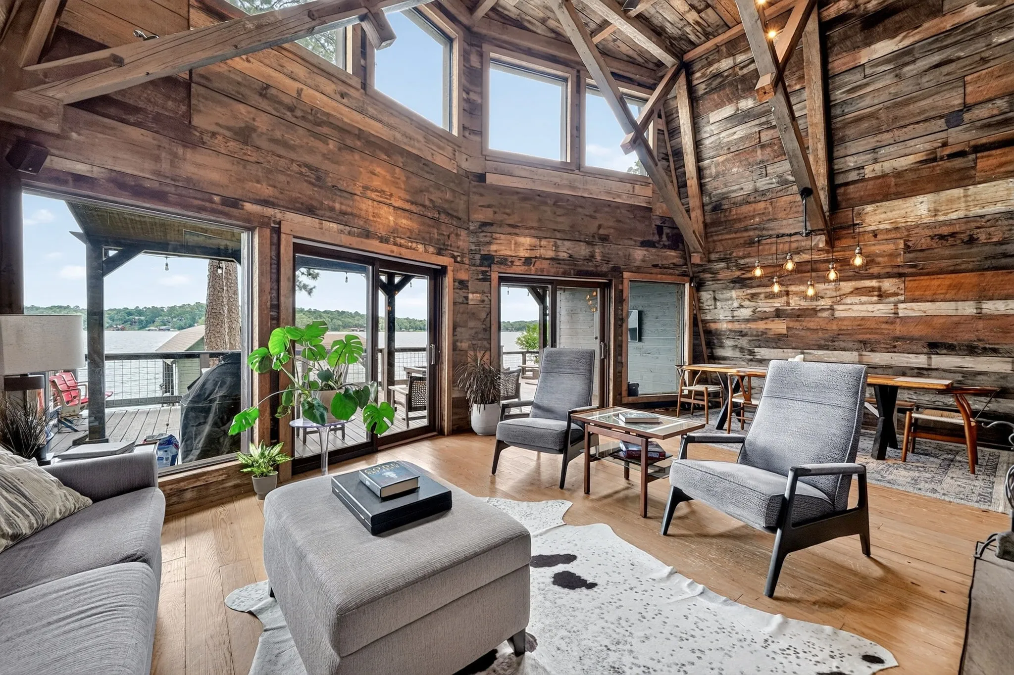 Living area featuring extensive wood-finish wall and ceiling cladding, exposed wood beams, and multiple sliding glass doors opening to an outdoor deck