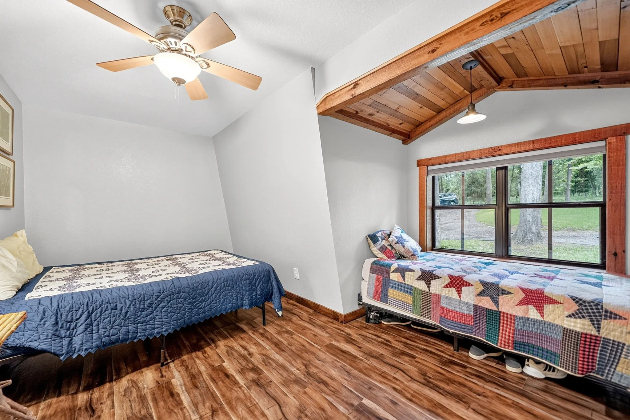 Interior room featuring wood-finish flooring, a ceiling fan with integrated lighting, and a large window with wood trim