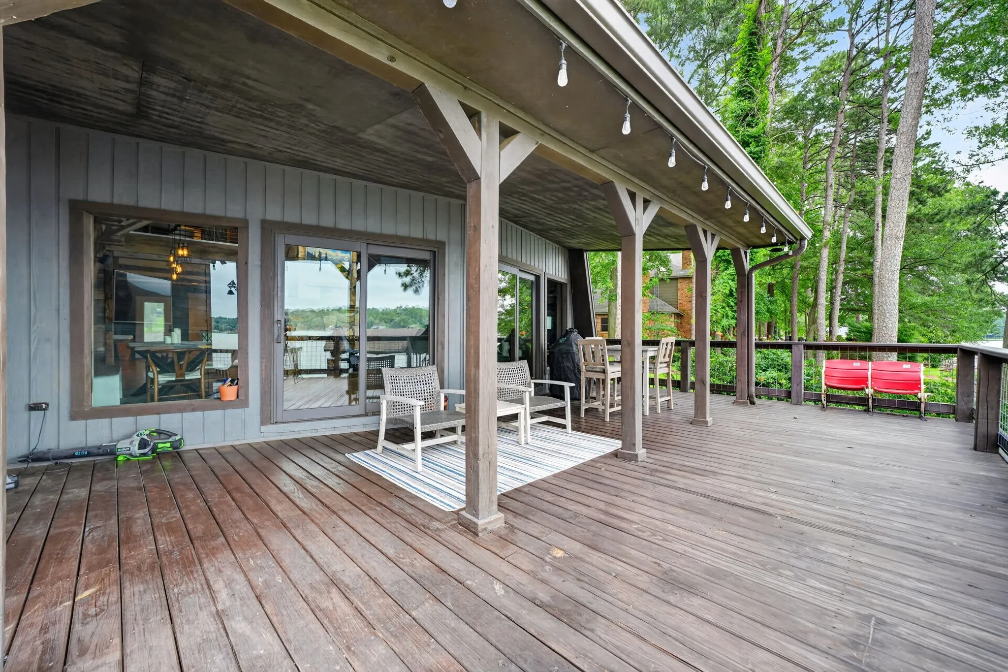 Spacious wood deck featuring an extended covered area with string lighting