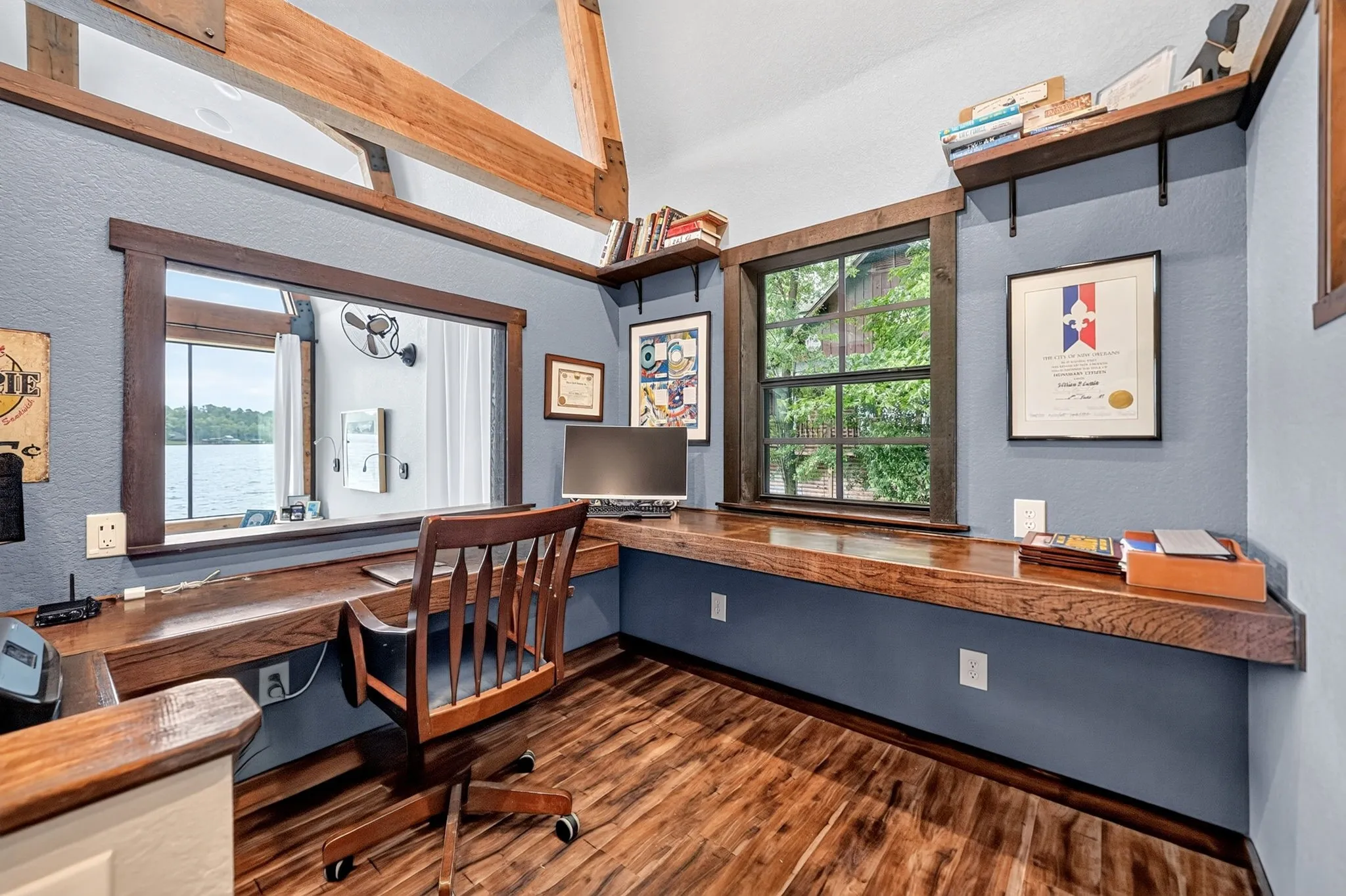 Interior room featuring wood-finish flooring, a built-in wood desk, and wood-framed windows