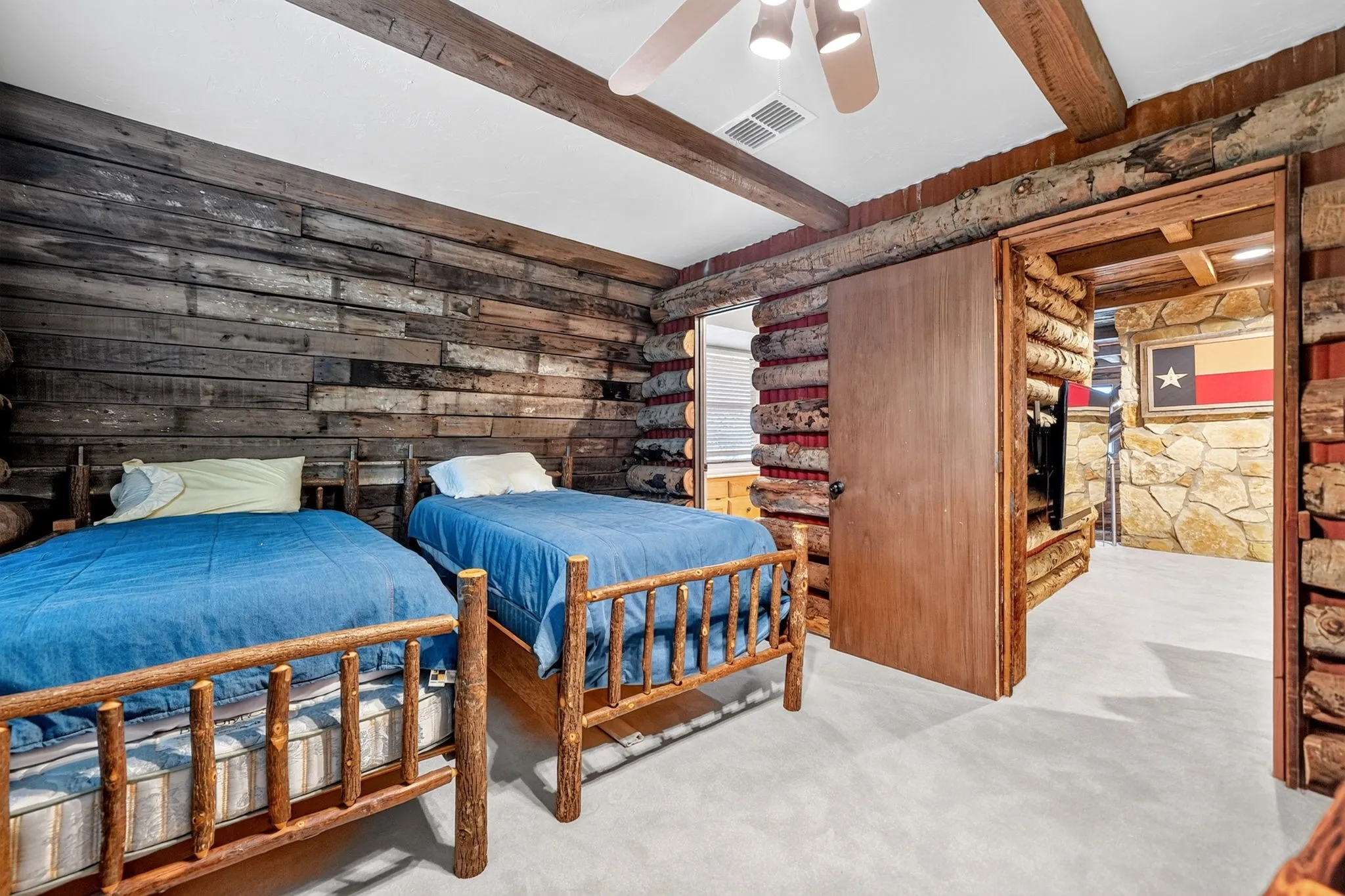 Rustic-style room featuring wood-plank accent walls, exposed ceiling beams, and light-colored carpeting