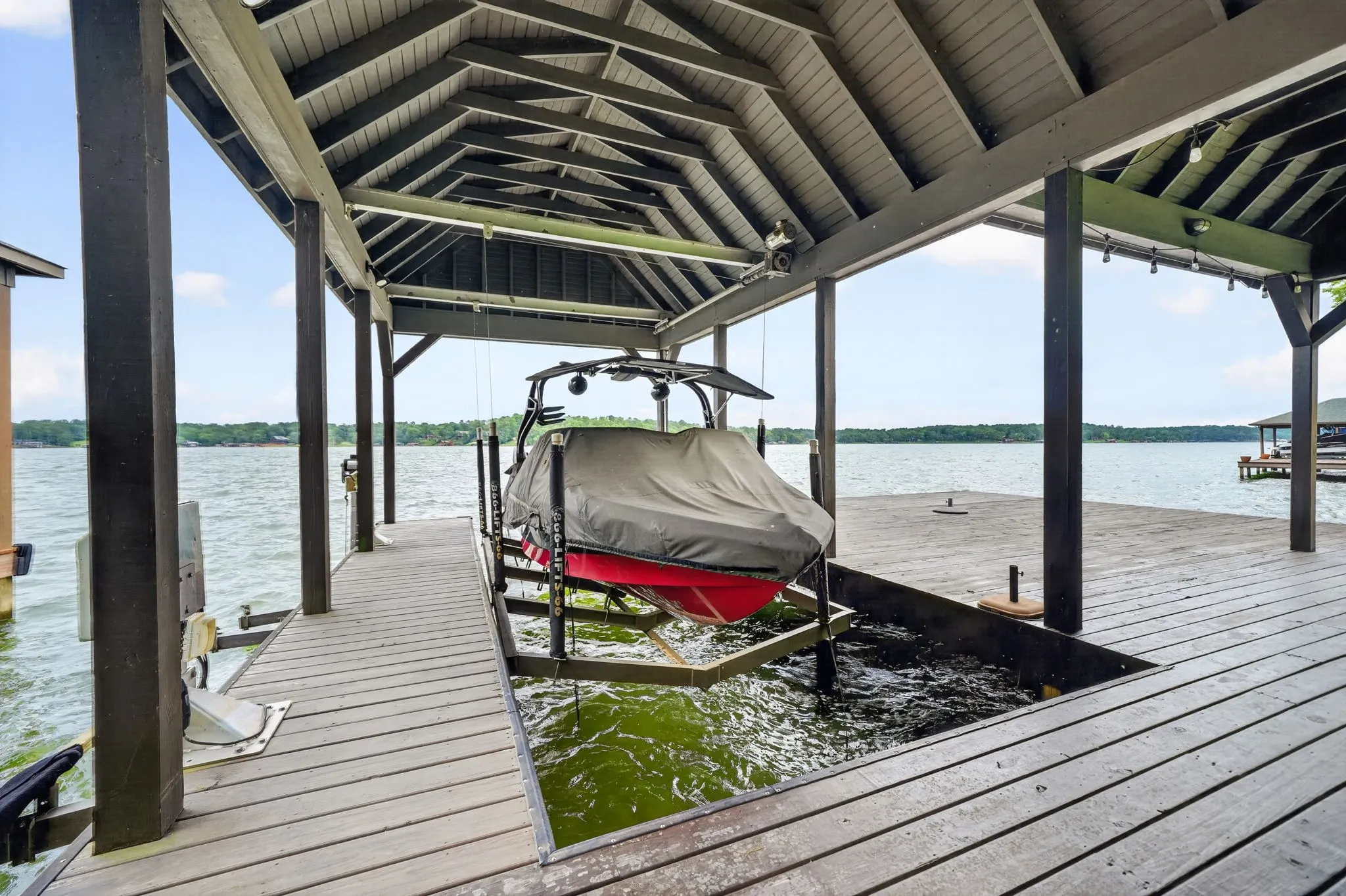 Expansive wooden deck overlooking a lake, featuring a railing with wire infill