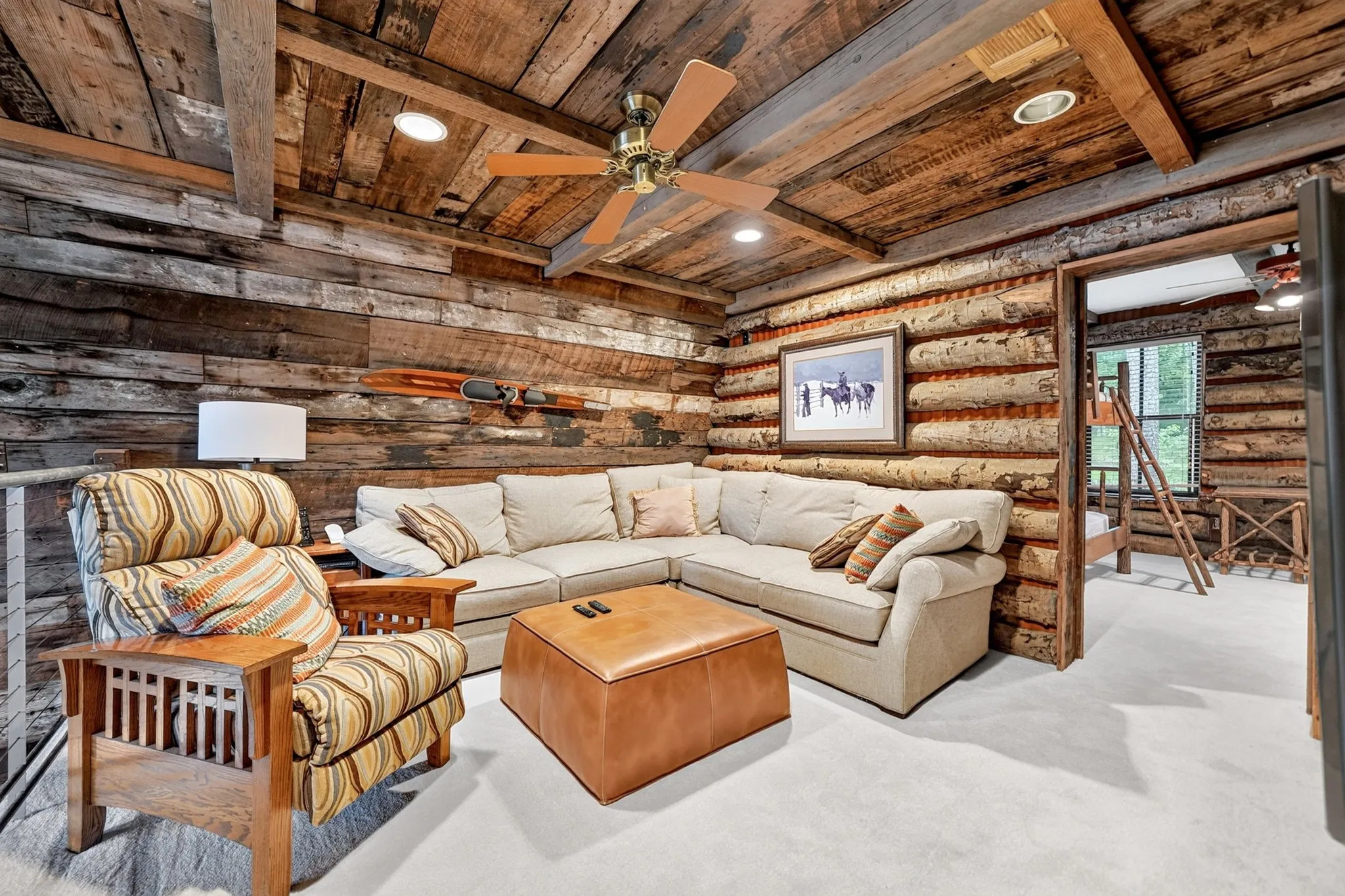 Living area featuring distressed wood plank walls, exposed beam ceiling with recessed lighting, and a ceiling fan