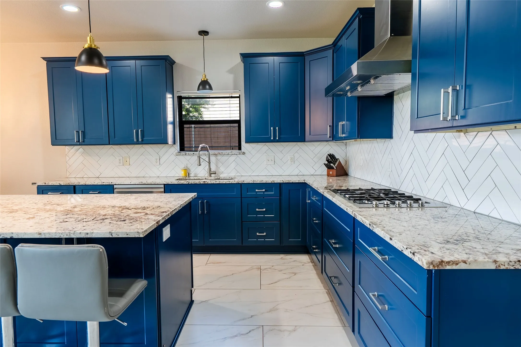 Kitchen featuring blue shaker-style cabinetry, light-toned countertops, a herringbone tile backsplash, a built-in gas range, and recessed lighting