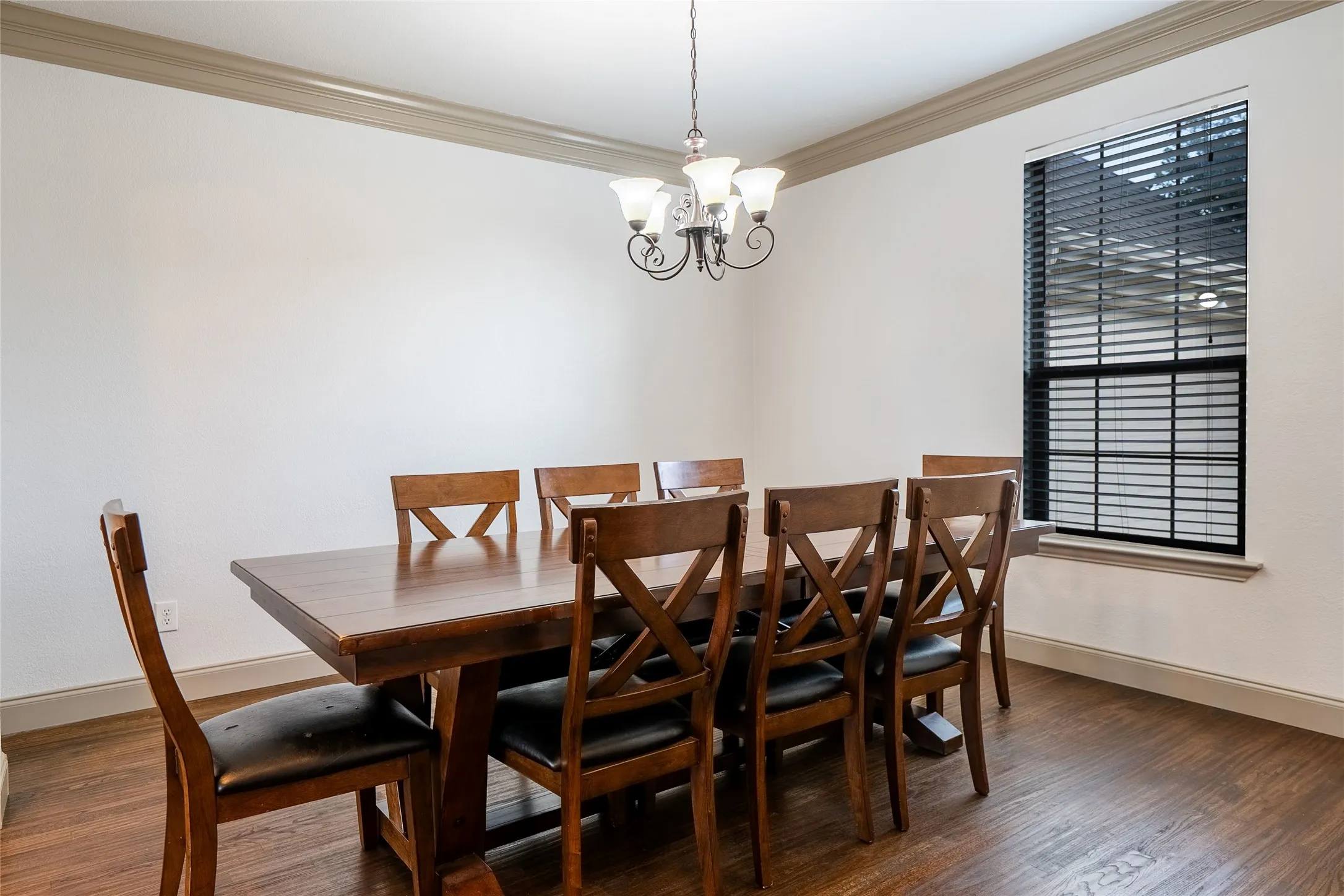 Dining area featuring wood-finish flooring, a single window with blinds, and a chandelier light fixture