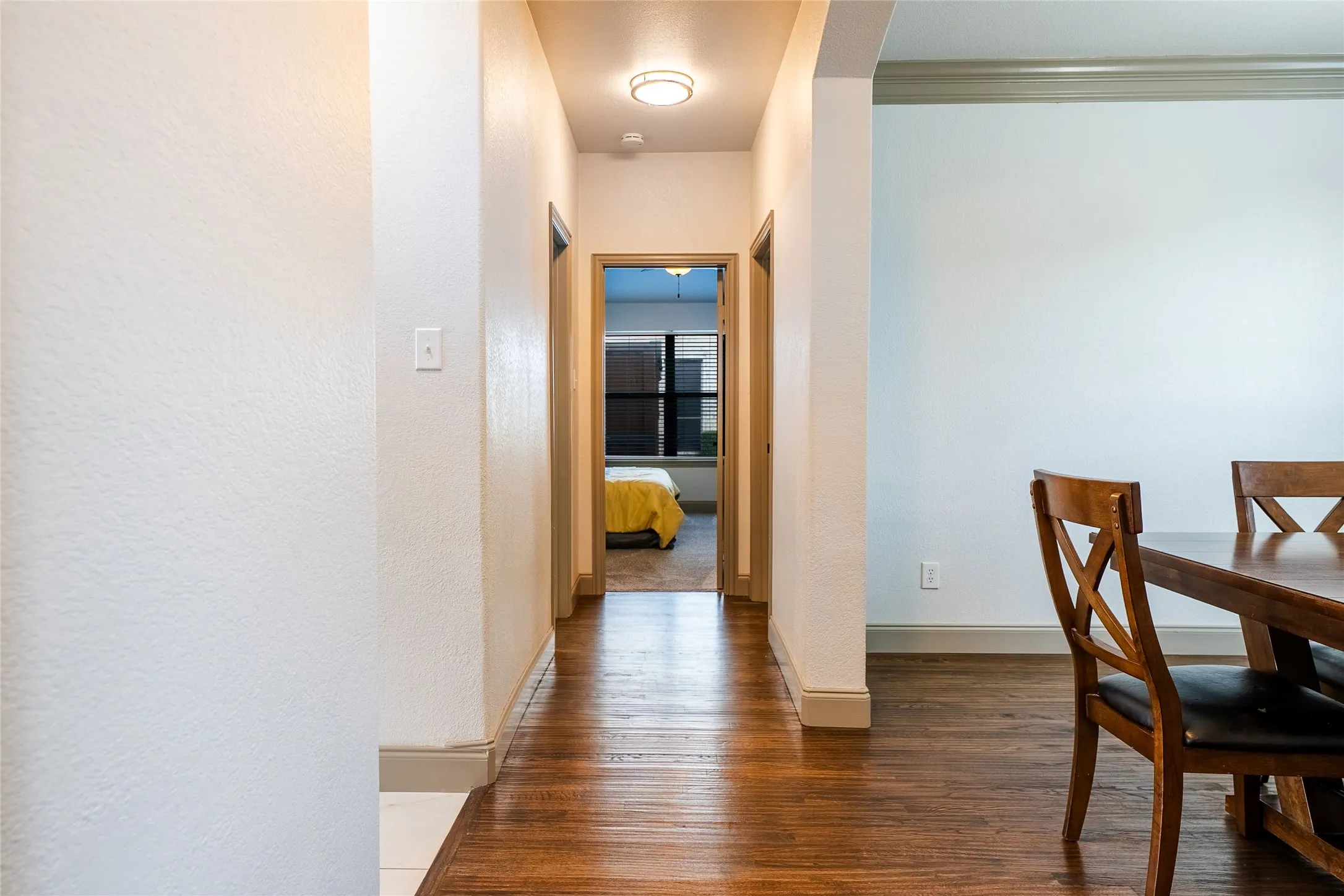 Hardwood-finish flooring extending through a hallway with white walls and baseboards
