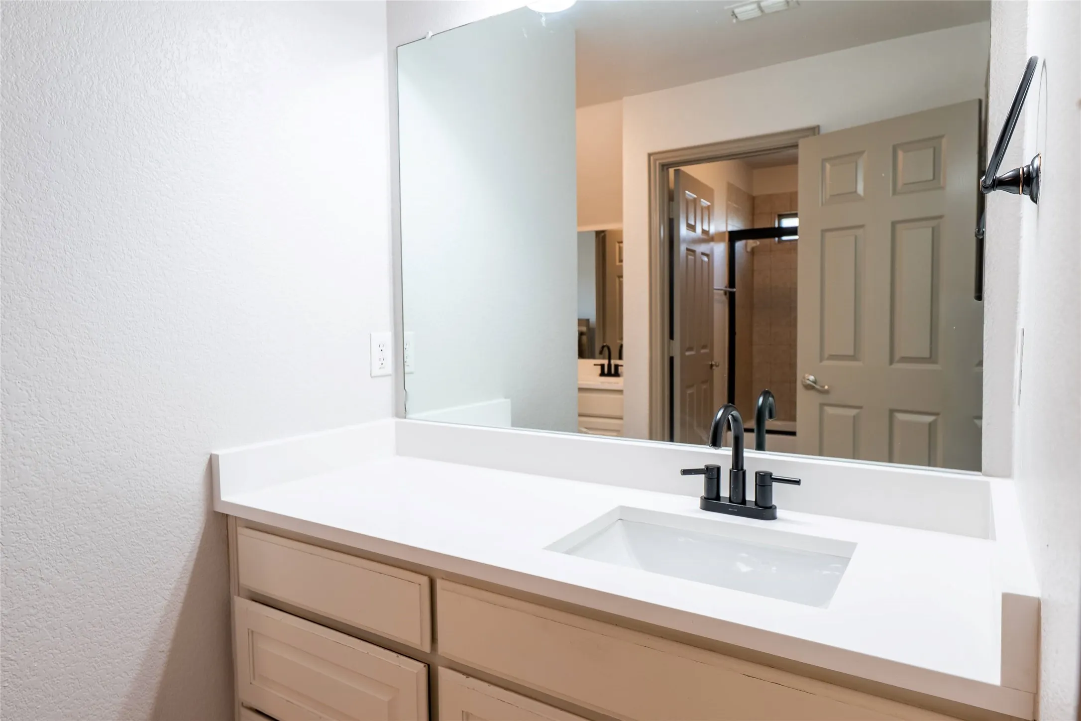 Bathroom vanity featuring a white countertop, undermount sink, and matte black faucet