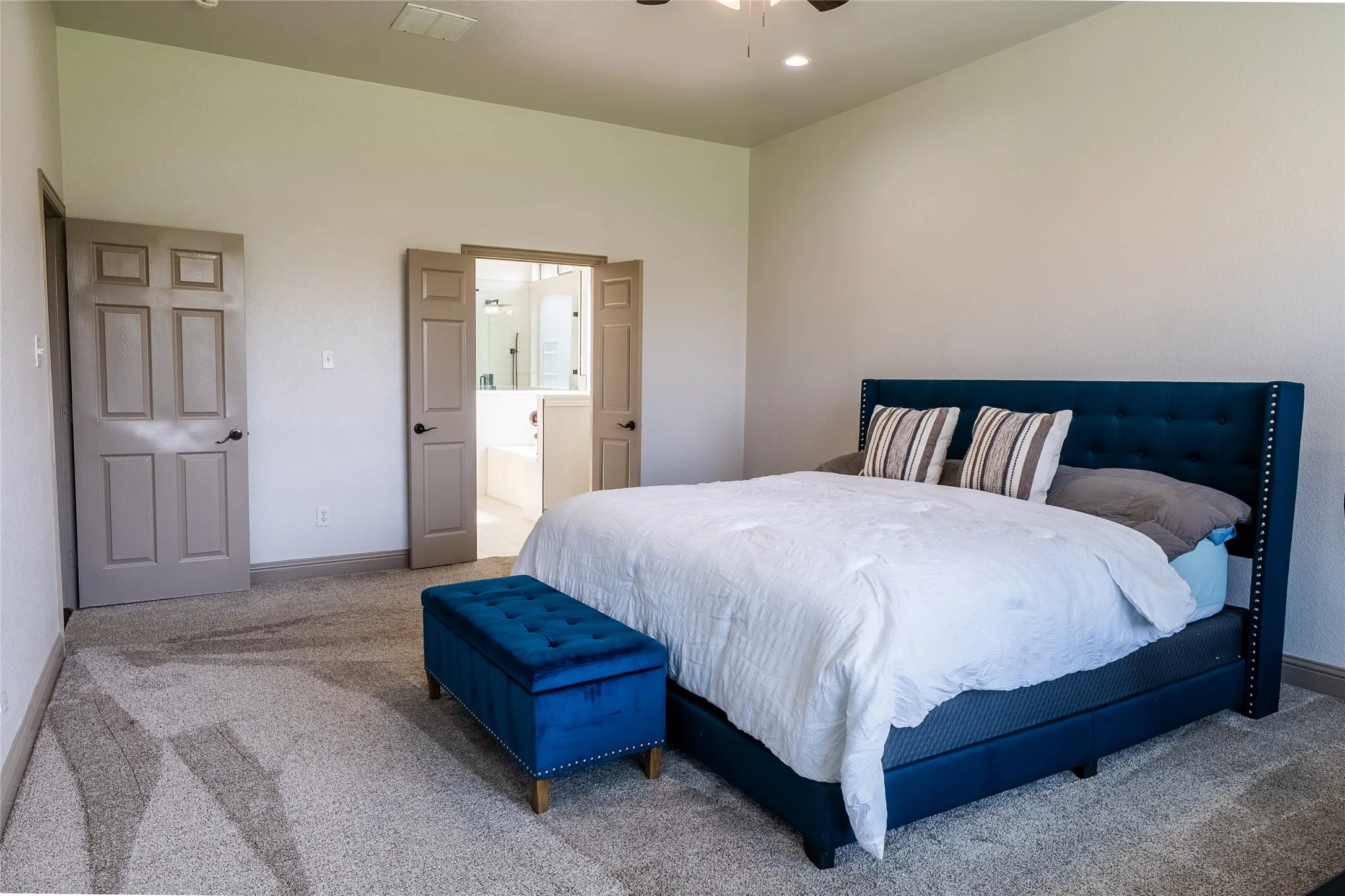 Spacious bedroom featuring light-colored walls and soft carpet flooring