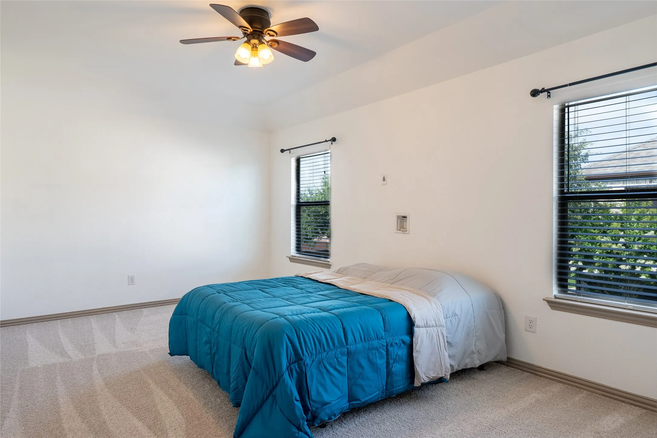 Spacious room featuring neutral carpeting, light-toned walls, and a ceiling fan with integrated lighting