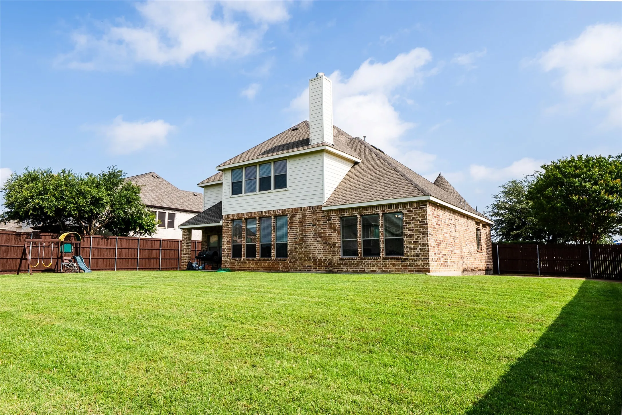 Expansive green lawn with a two-story brick and siding exterior