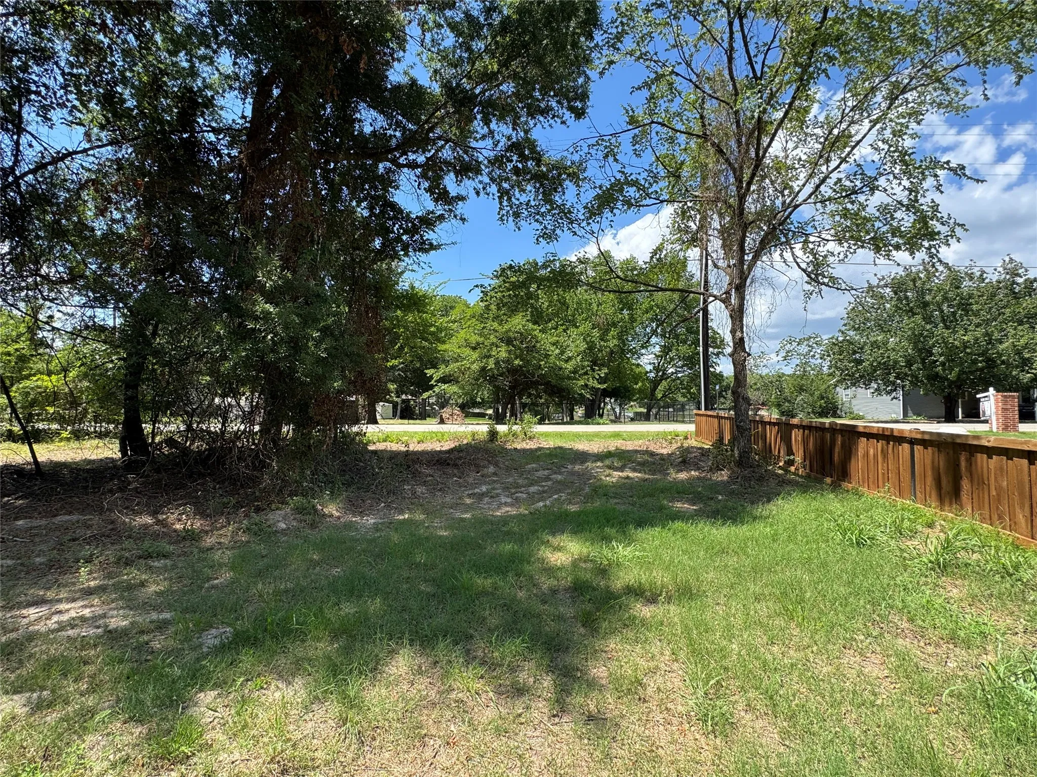 Expansive residential lot featuring mature trees and a private wood fence