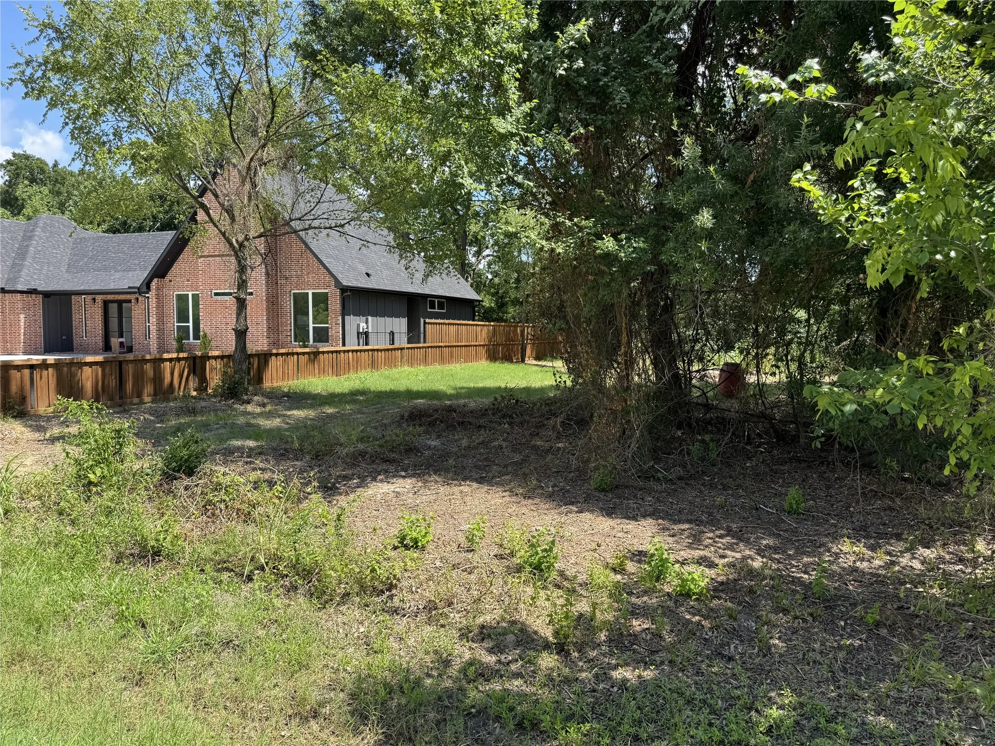 Residential lot featuring mature trees and a partial wood fence