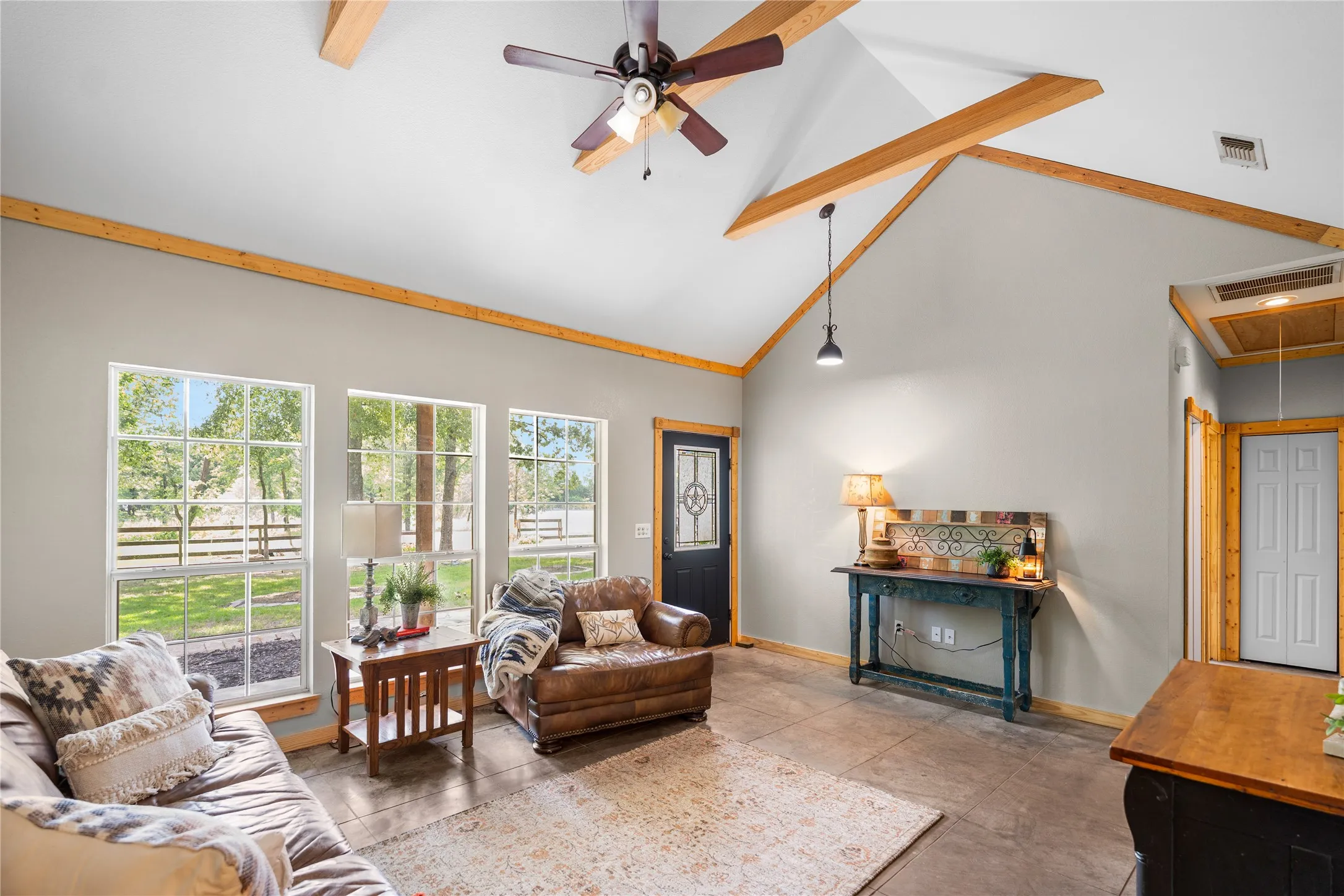 Vaulted ceiling with exposed wood beams, ceiling fan, and pendant lighting