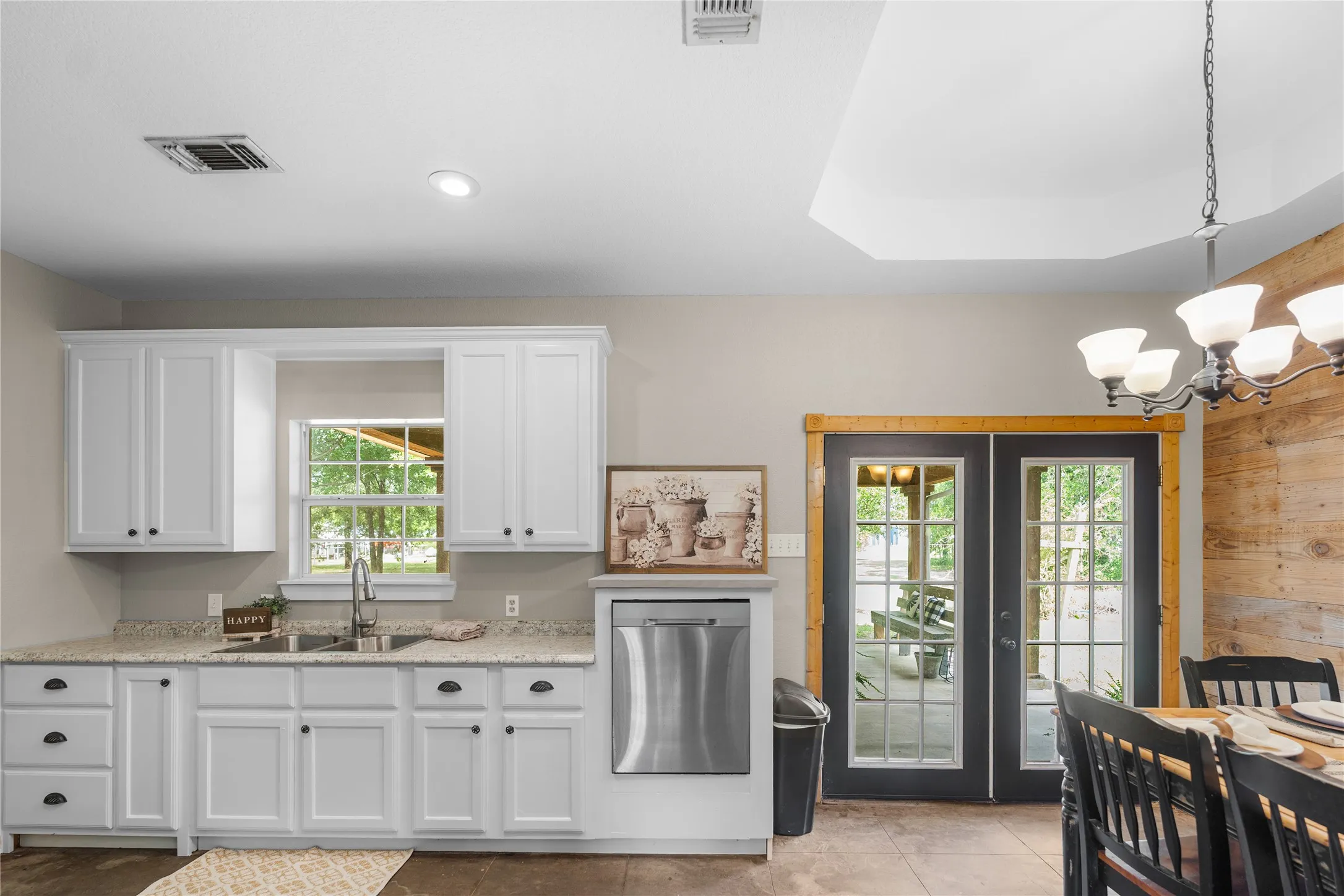 Kitchen area featuring white shaker-style cabinetry, a dual basin stainless steel sink, and light-toned countertops