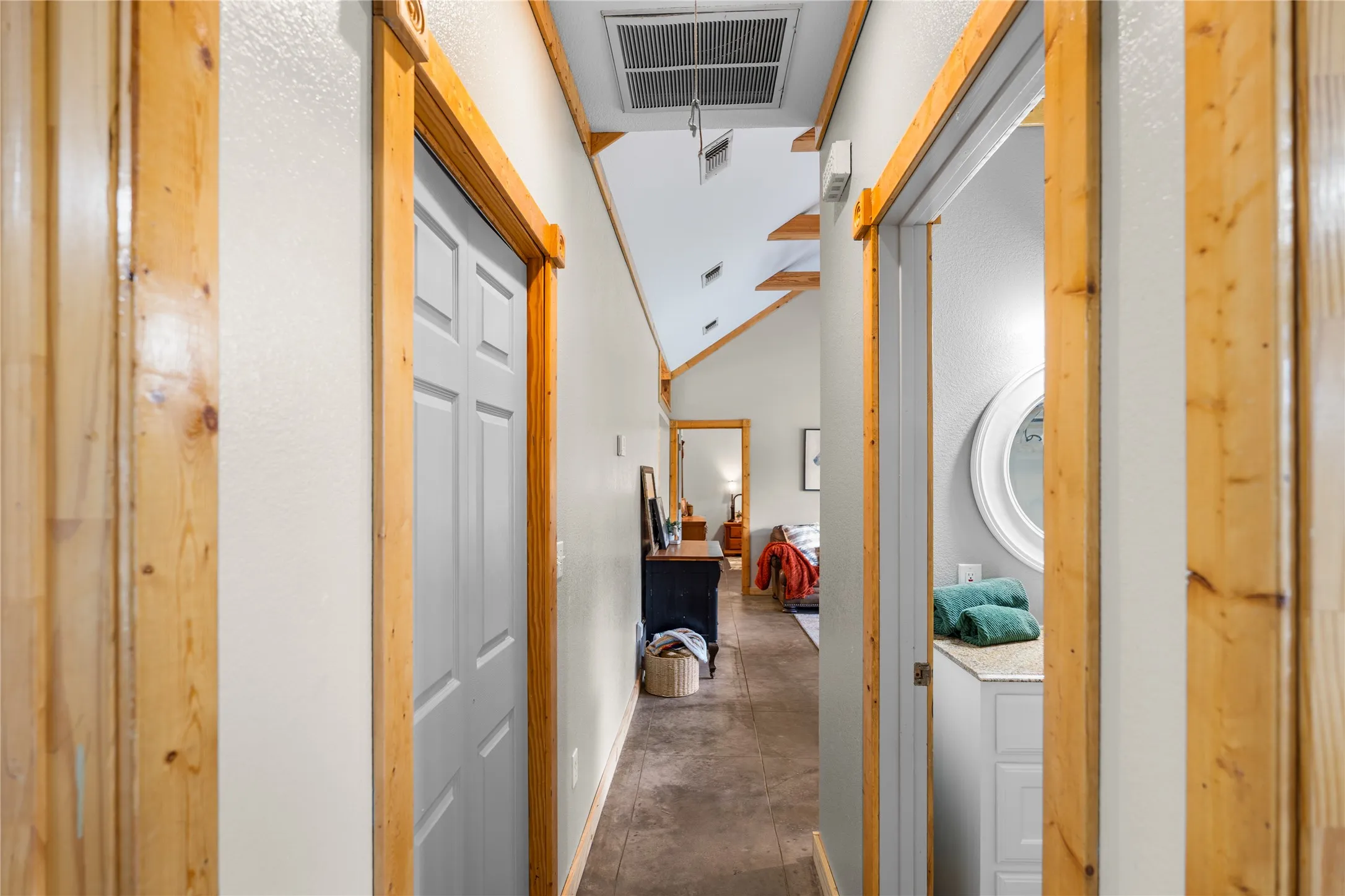 Hallway featuring natural wood trim, white panel doors, vaulted ceiling, and recessed lighting