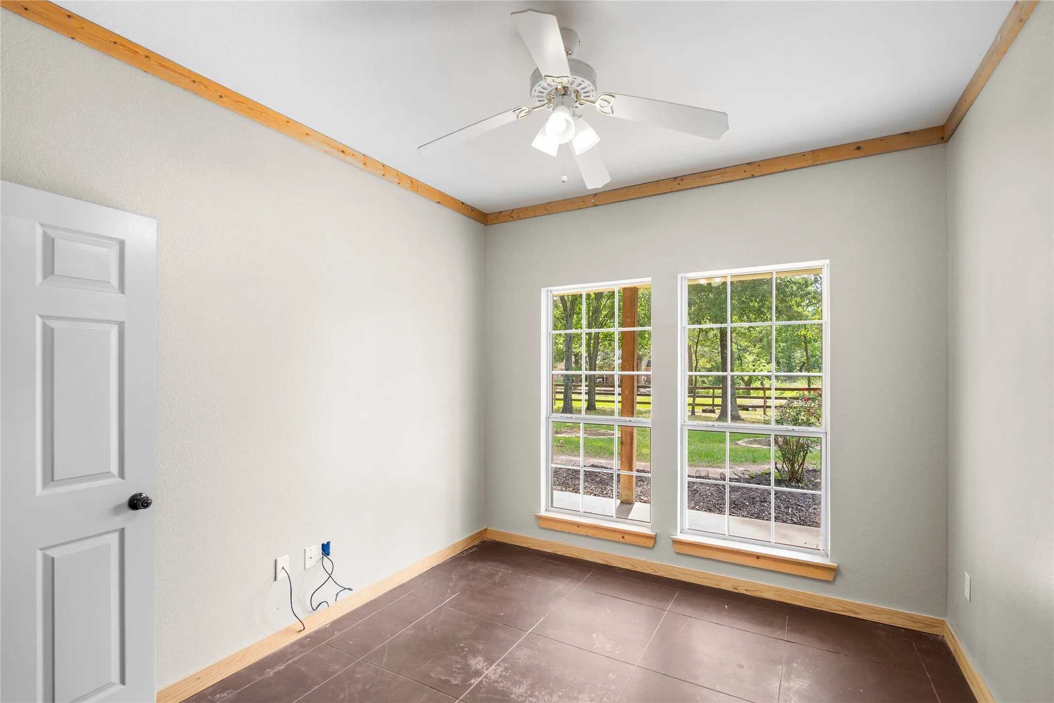 Room featuring two large windows with grid muntins, wood-finish trim, and a white ceiling fan
