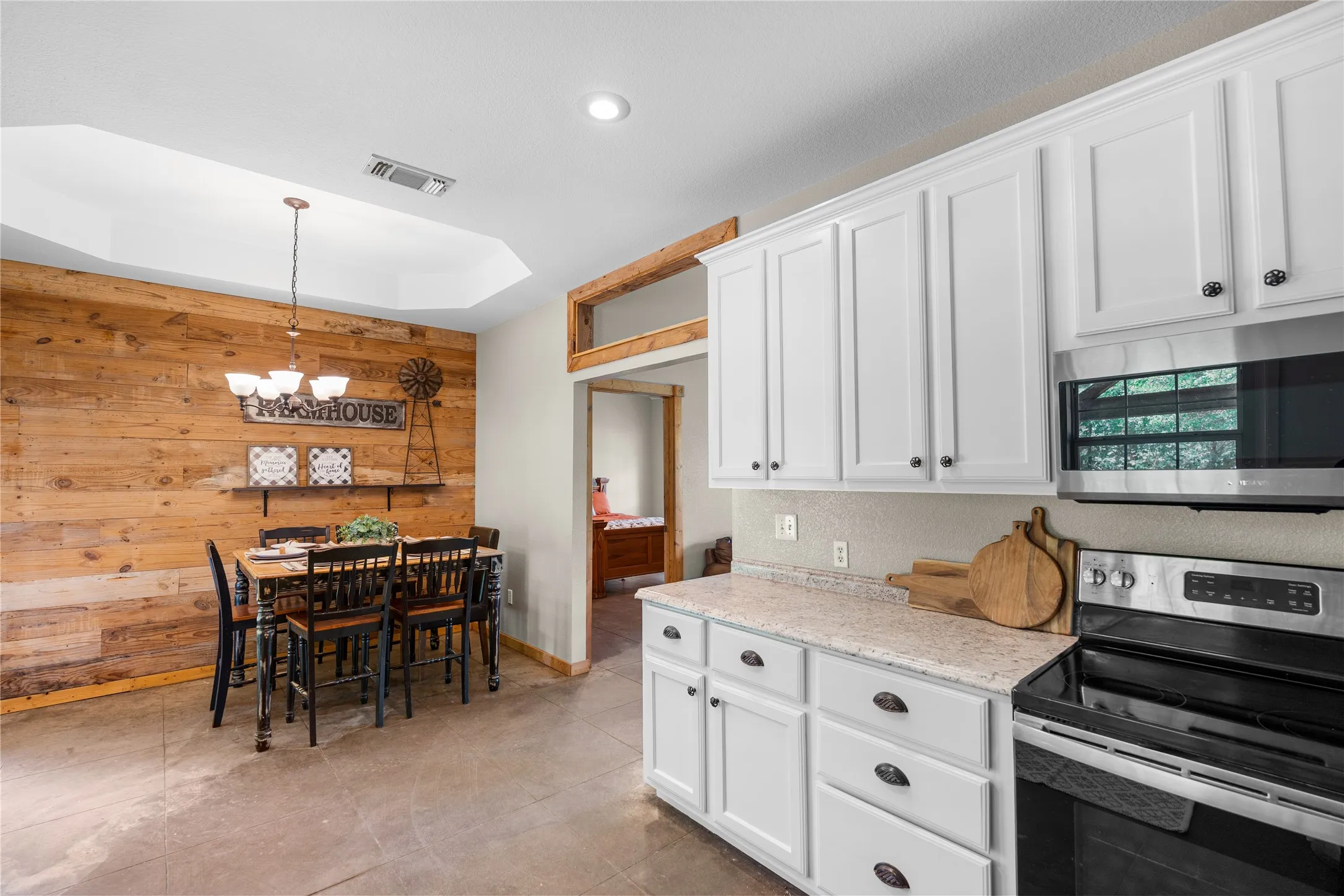 Kitchen and dining area featuring white cabinetry, light-toned countertops, and a full suite of stainless steel appliances including a built-in microwave and electric range