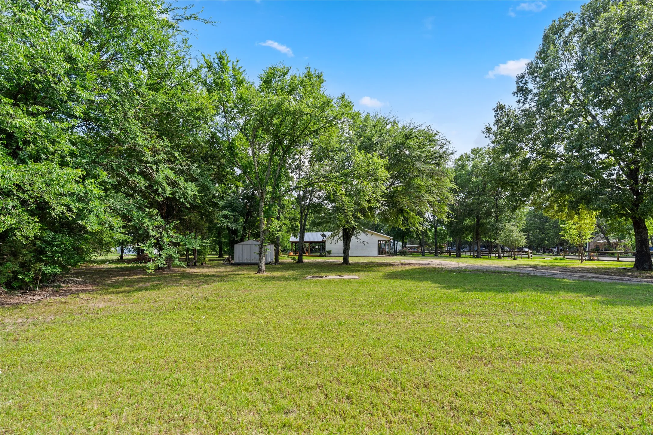 Expansive green lawn with mature trees and a clear blue sky