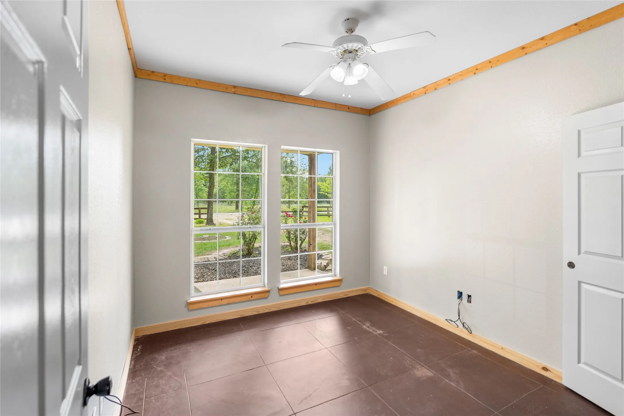 Interior room featuring two large windows, wood-finish flooring, and crown molding