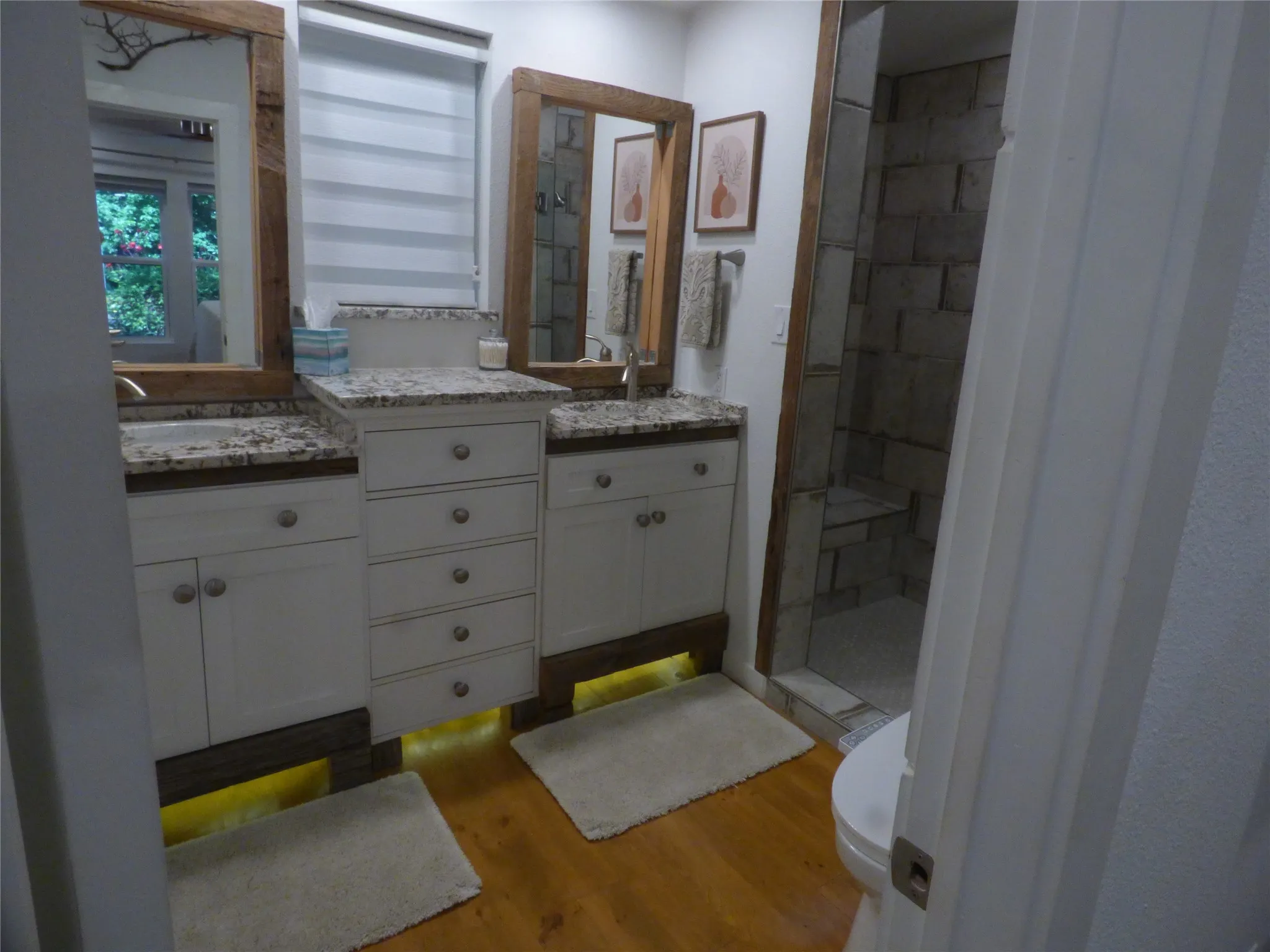 Dual vanities with granite-finish countertops, white cabinetry, and undermount lighting