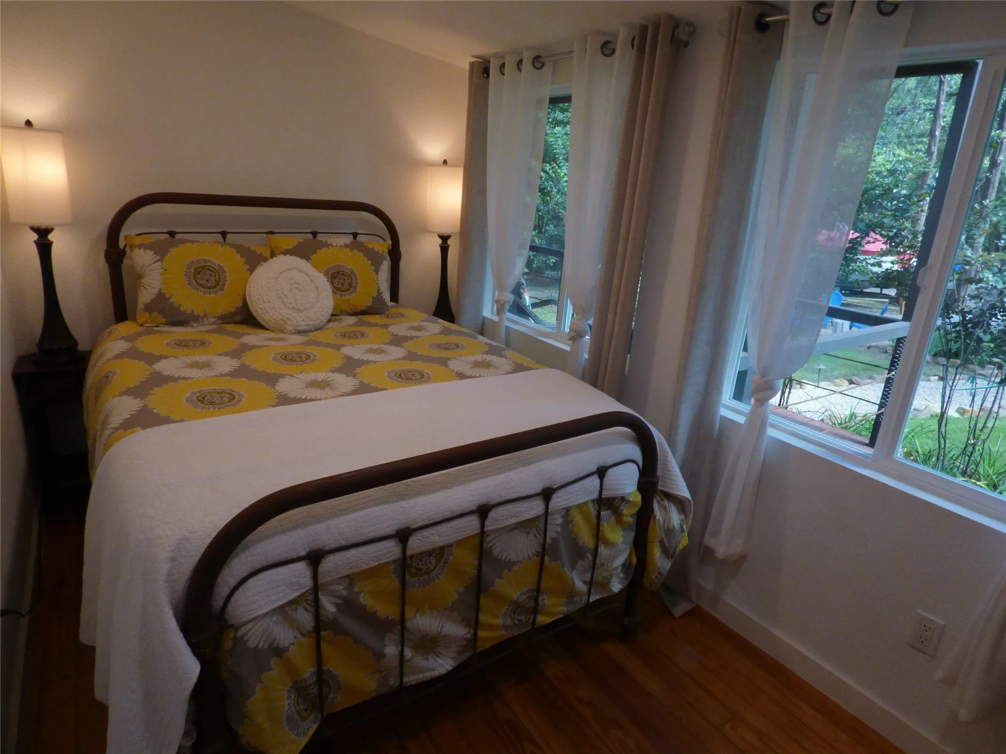 Bedroom featuring wood-finish flooring, white walls, and multiple windows with white trim