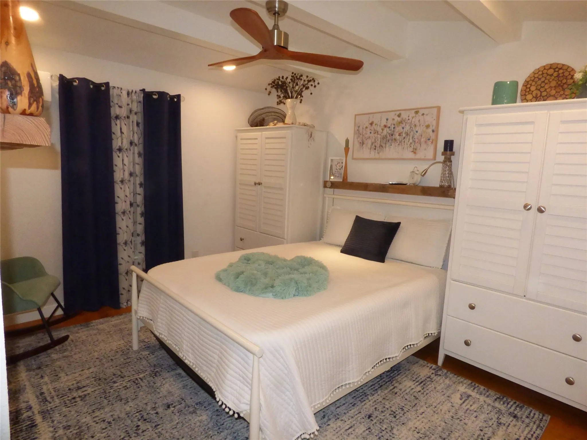 Inviting room featuring a white bed frame, white walls, and a ceiling fan with integrated lighting