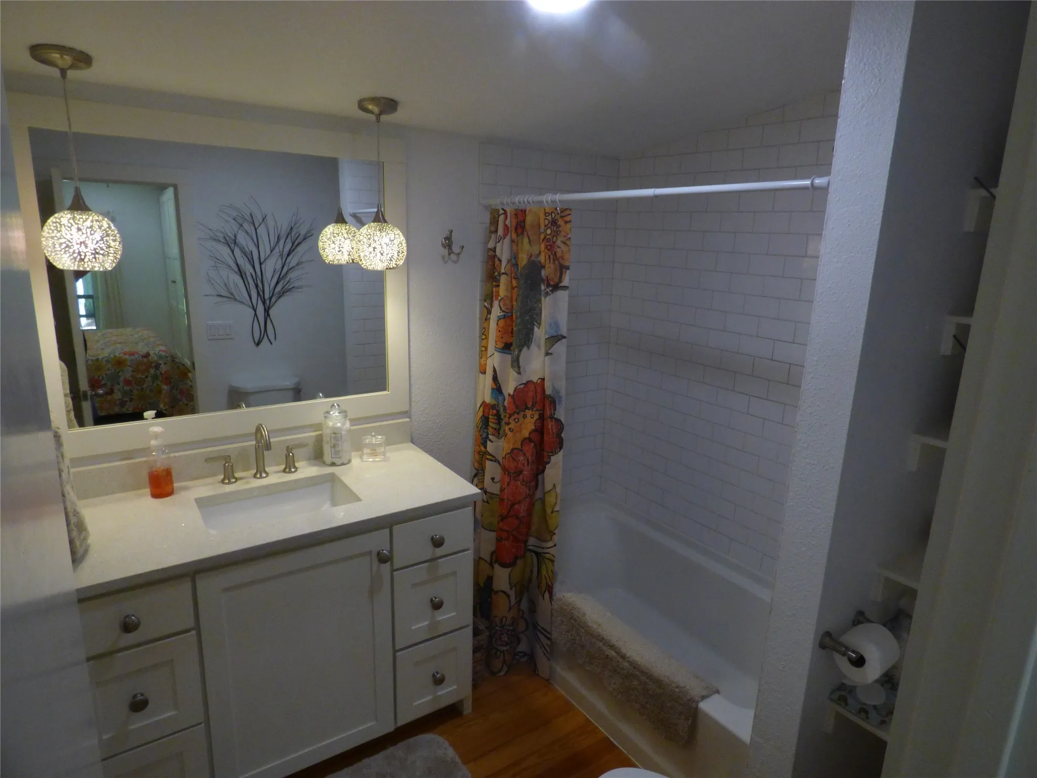 Bathroom featuring a white vanity with an undermount sink and brushed nickel faucet, light-toned countertop, and two pendant light fixtures