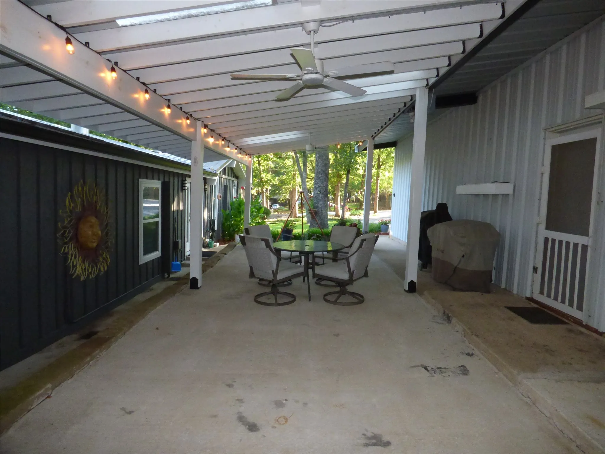 Expansive concrete patio featuring a white slatted pergola