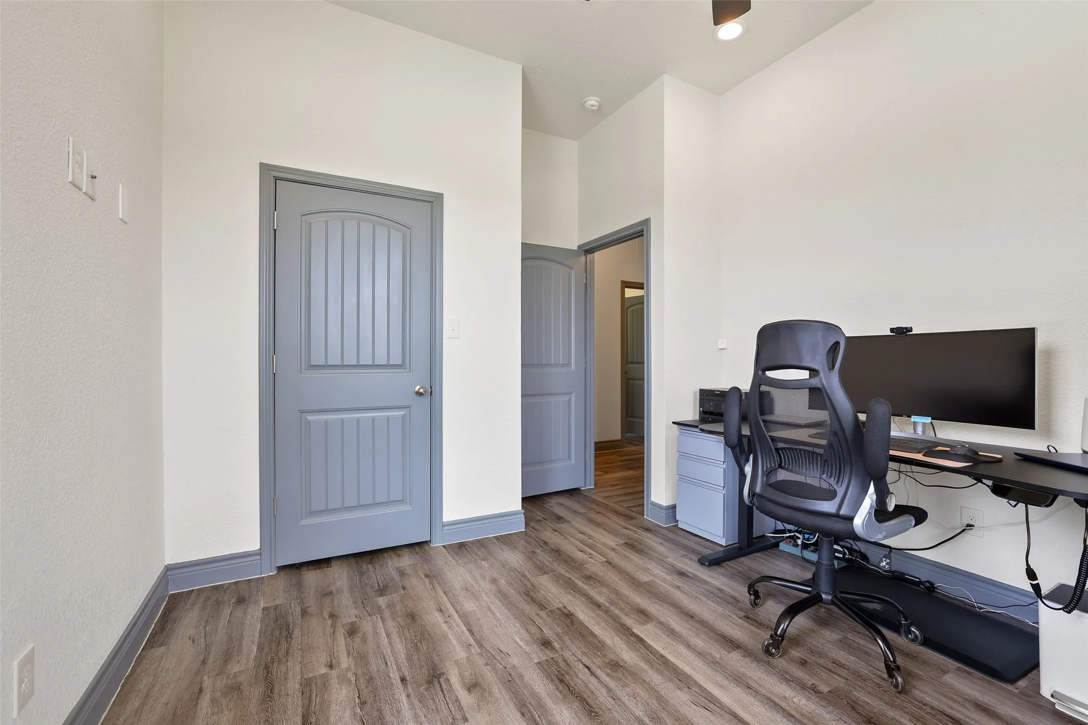 Room featuring wood-finish flooring, white walls, and a light gray trim