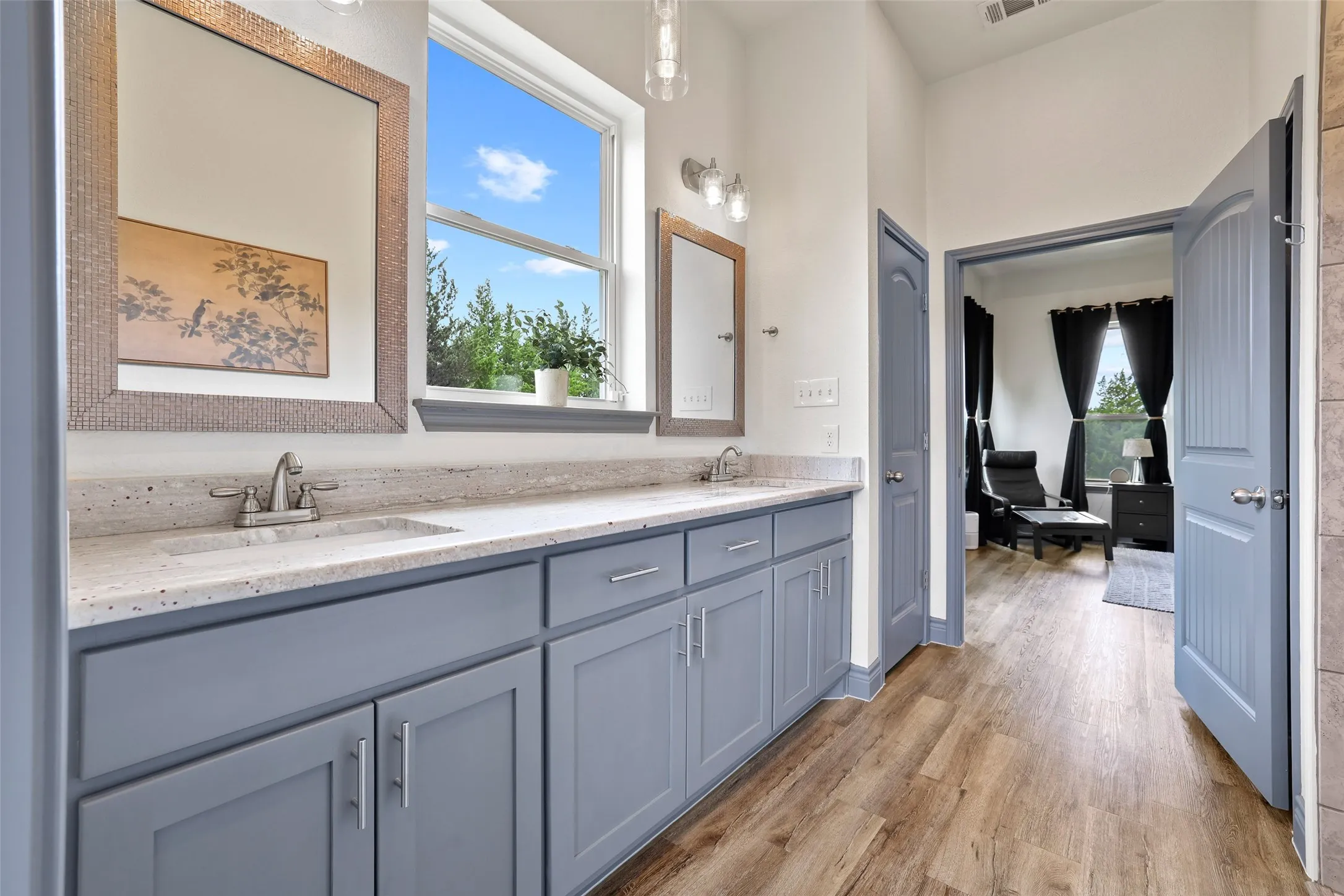 Double vanity with stone countertop, undermount sinks, and wood-finish flooring