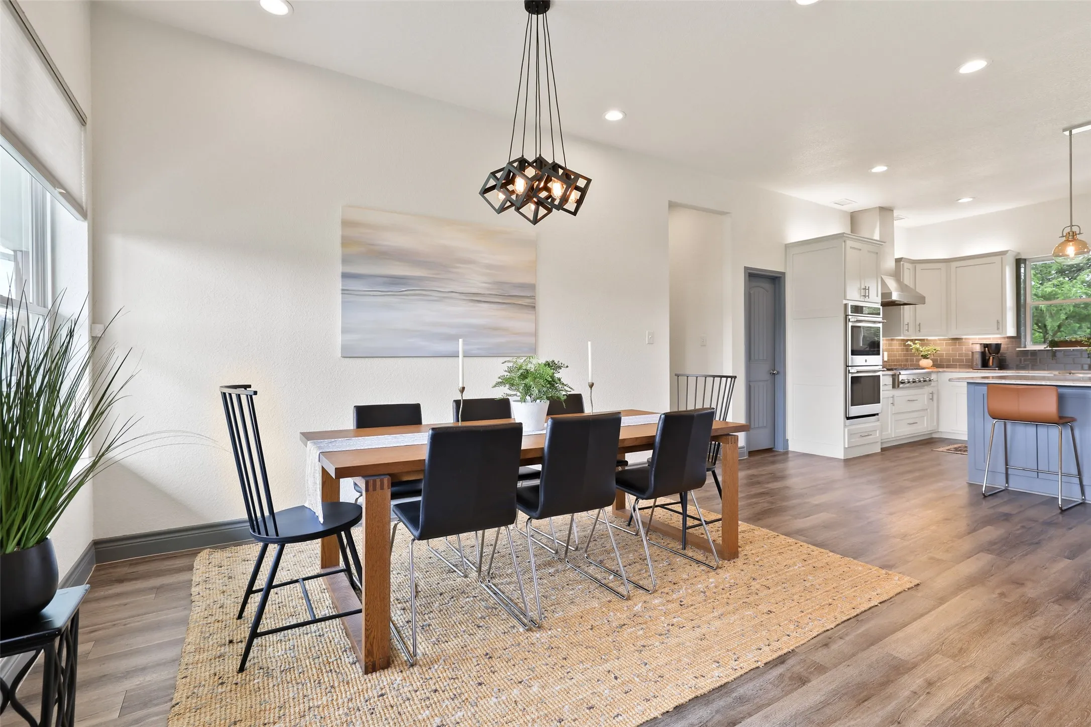 Dining area with wood-finish flooring and a contemporary geometric chandelier