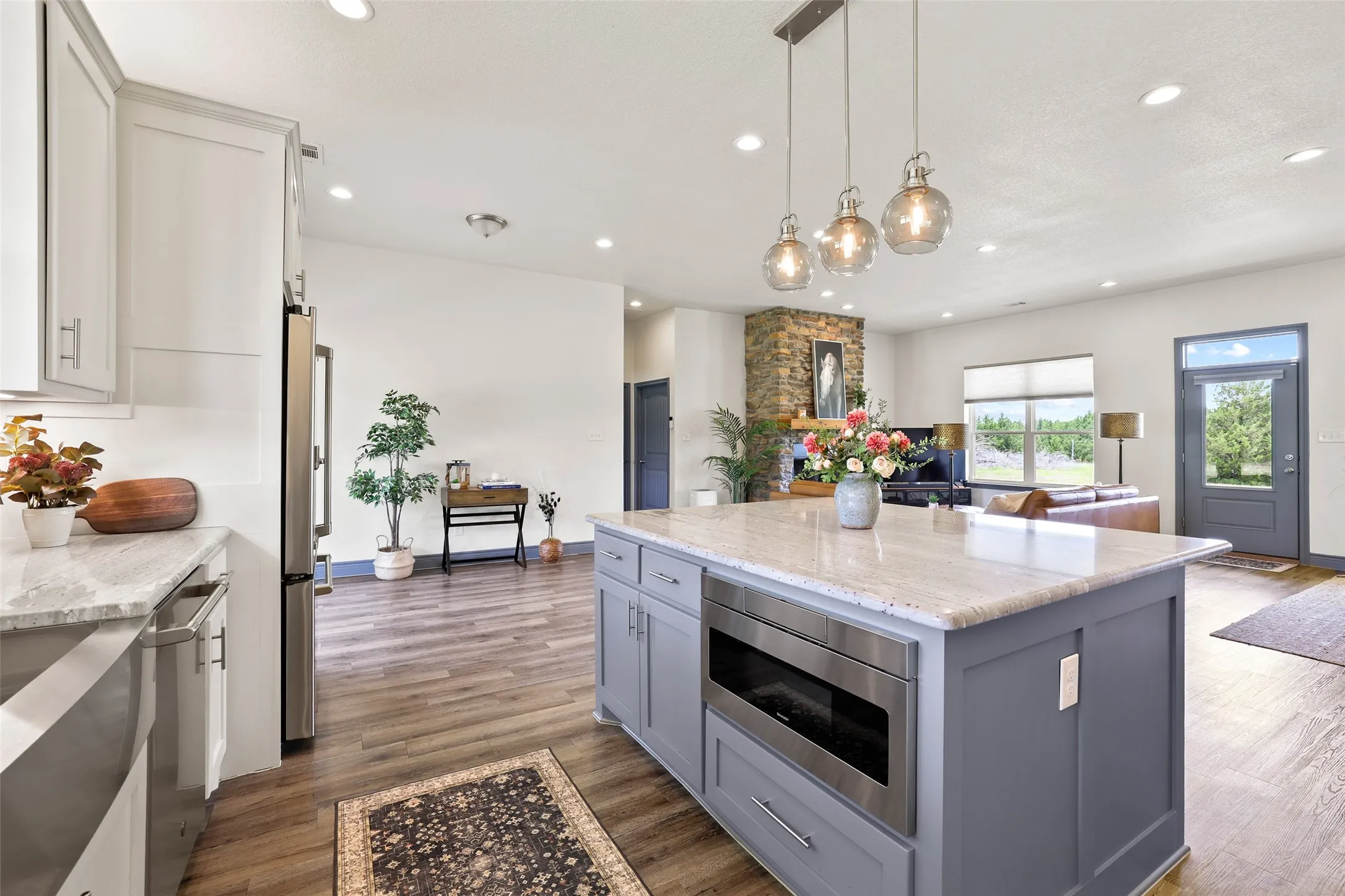 Kitchen featuring a center island with pendant lighting, integrated microwave, and a light-toned countertop