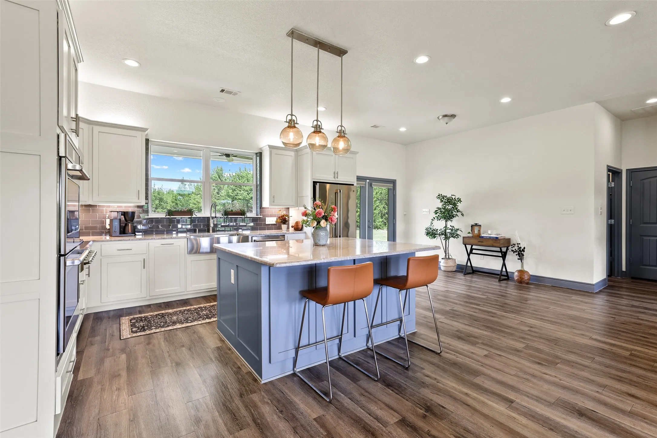 Open-concept kitchen and living area featuring wood-finish flooring, recessed lighting, and a kitchen island with pendant lighting