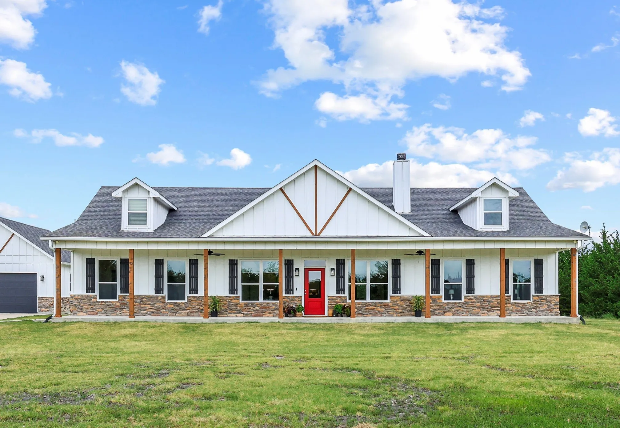 White siding exterior with a stone veneer foundation and a covered front porch featuring wood pillars