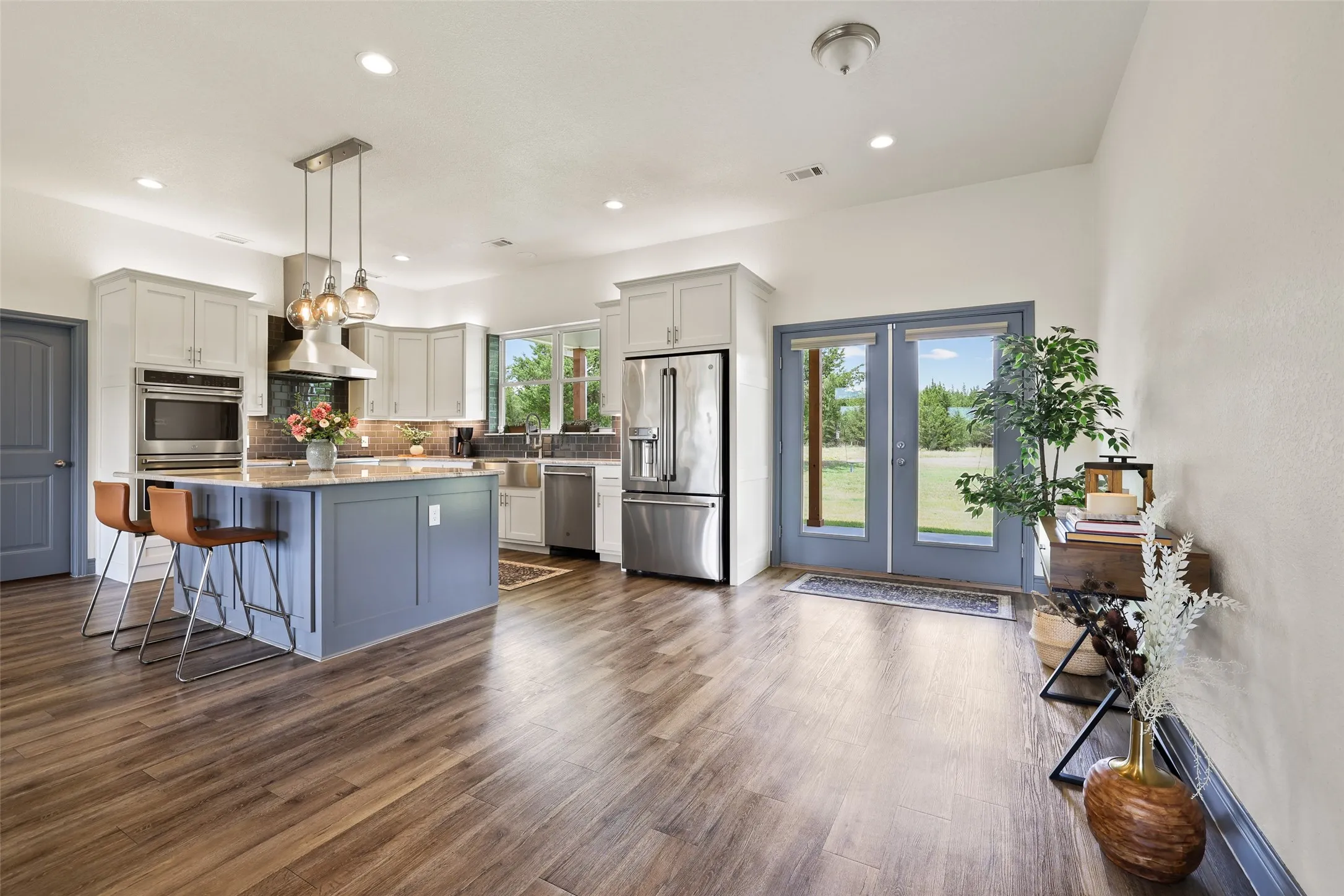 Open-concept kitchen featuring an island with seating, stainless steel appliances, recessed lighting, and wood-finish flooring