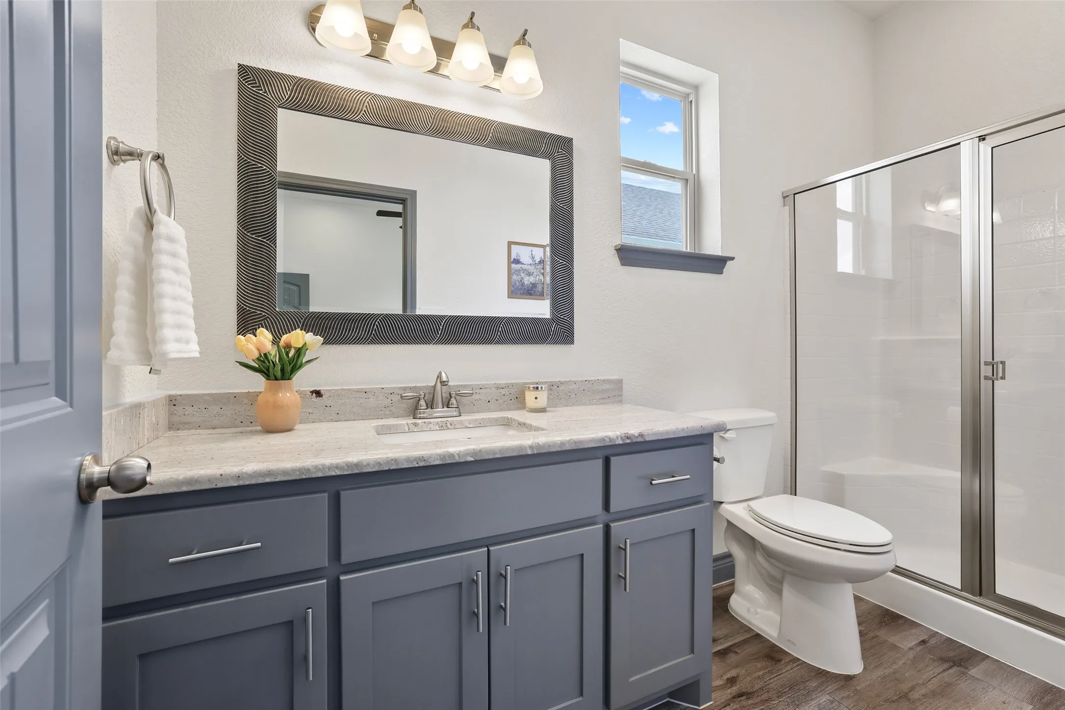 Un-Suite Bathroom featuring a modern vanity with a light-colored countertop, a framed mirror, and wood-finish flooring