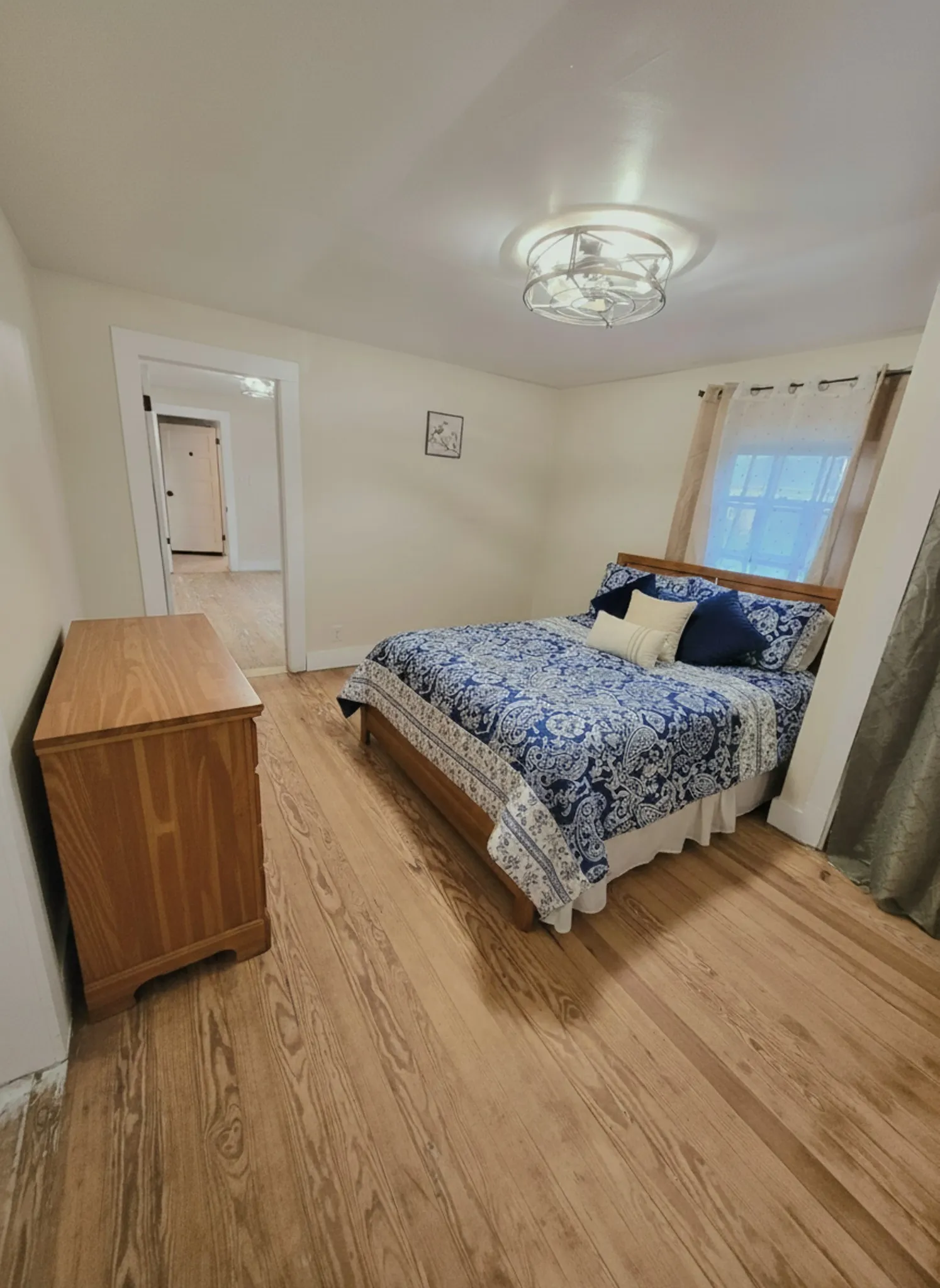 Wood flooring and a ceiling fan elevate the comfort in this inviting bedroom. DIGITAL STAGING