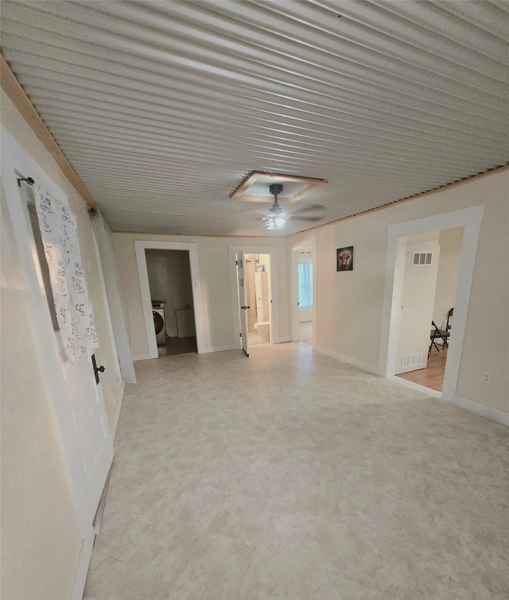 A versatile open space features durable vinyl flooring and a unique corrugated ceiling with a central fan.