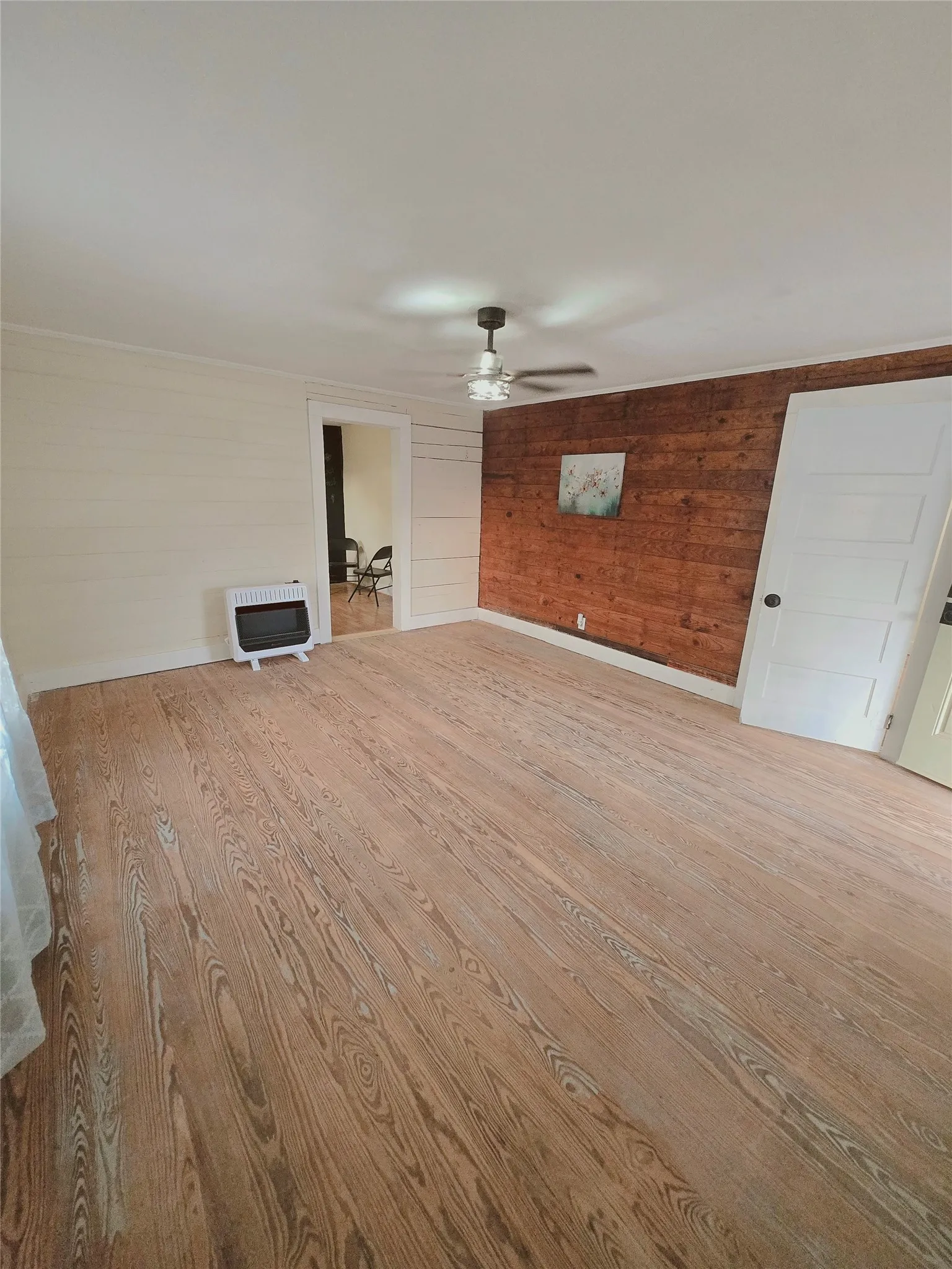 Warm wood flooring extends throughout this versatile living area, featuring a decorative accent wall.