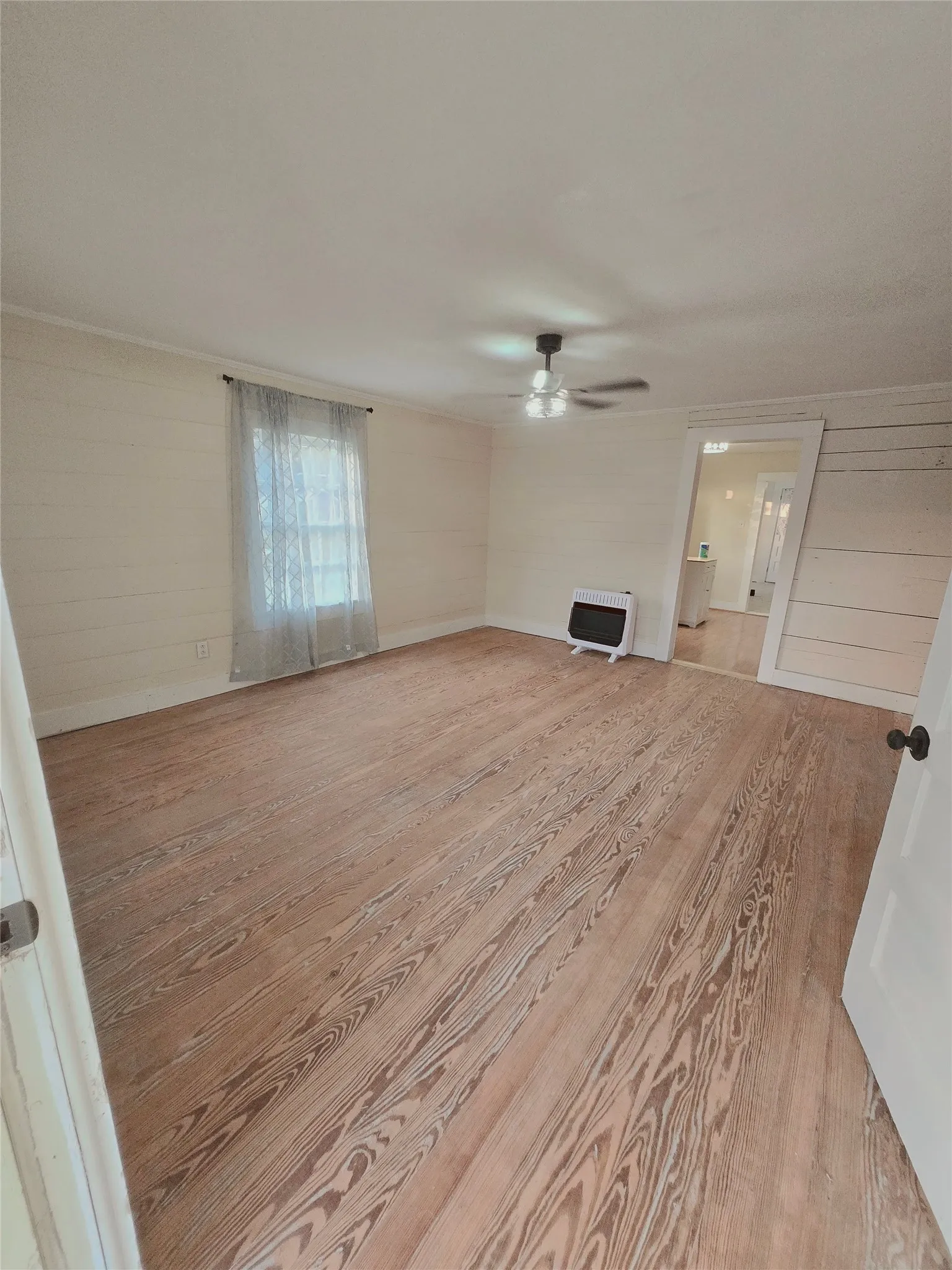 Natural wood flooring complements the airy ambiance of this adaptable interior space.