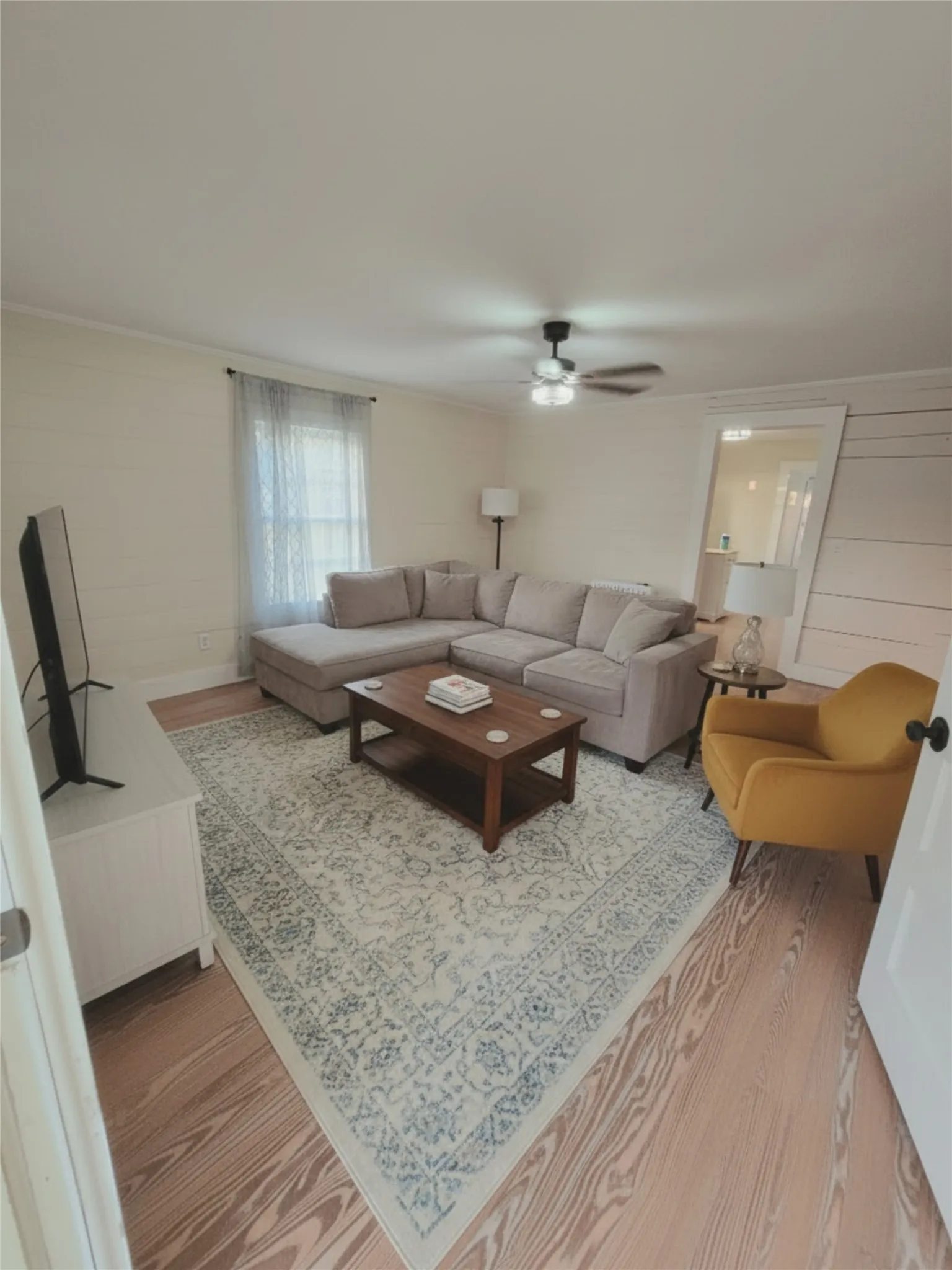 DIGITAL STAGING A comfortable living space featuring rich hardwood flooring and a stylish area rug. DIGITAL STAGING