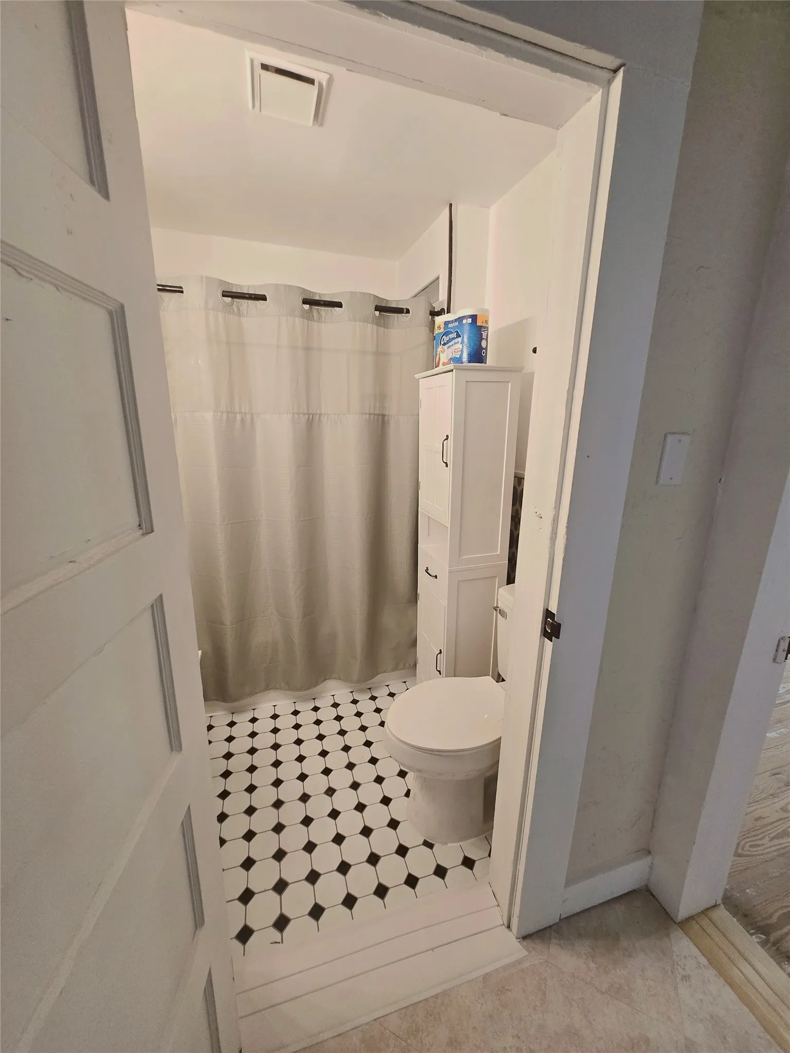 Black and white patterned tile flooring defines this tidy, bathroom with storage space.