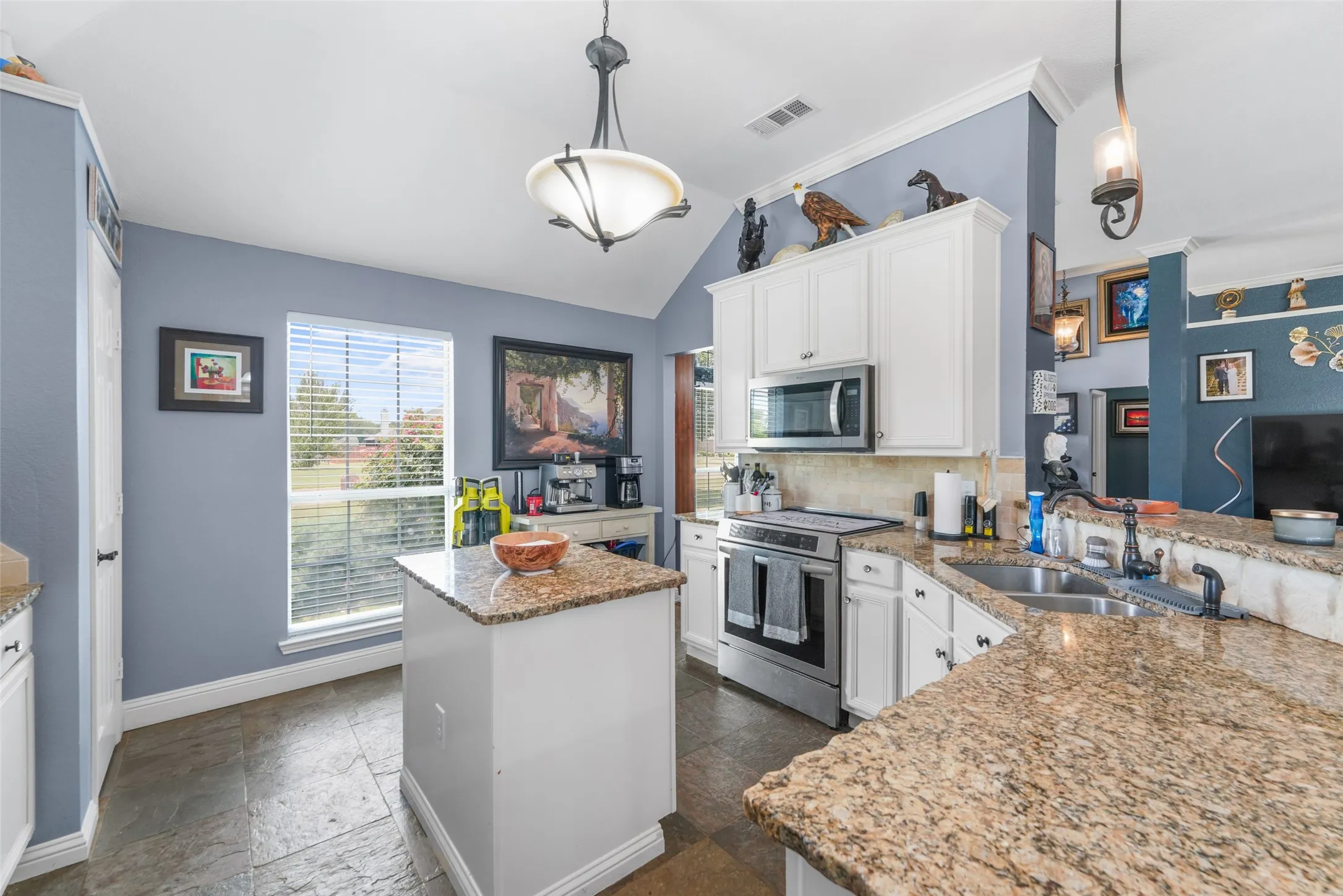 Kitchen featuring granite countertops, white cabinetry, a central island, stainless steel appliances, and tile flooring