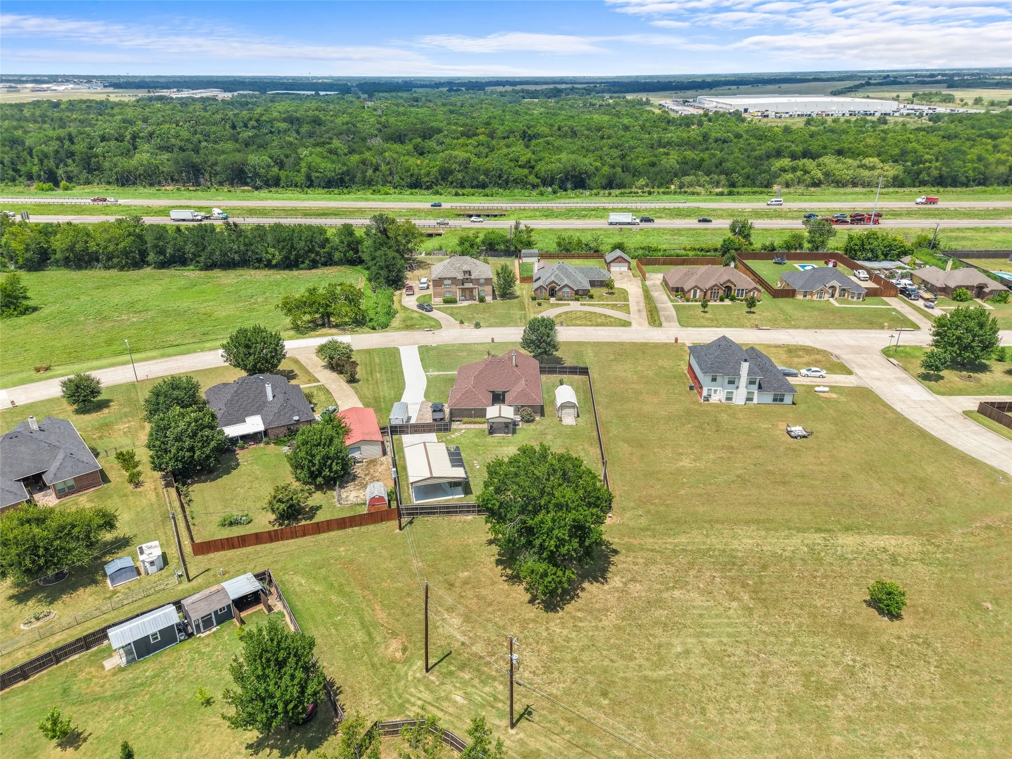 Aerial perspective showcasing a residential area with a prominent highway and expansive forested backdrop